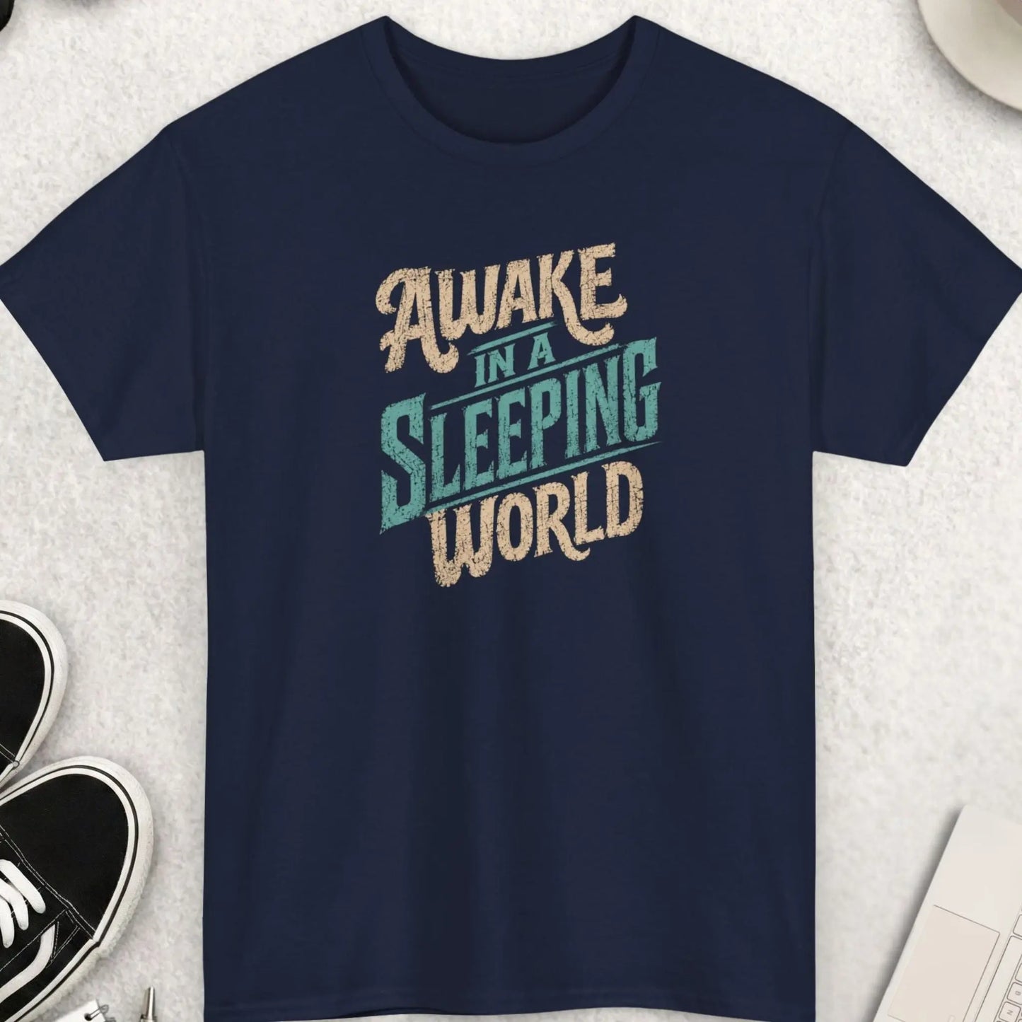 Awake In A Sleeping World vintage distressed awareness t-shirt featuring retro cream and faded blue typography on a navy blue shirt with worn graphic texture and inspirational independent thinker message.