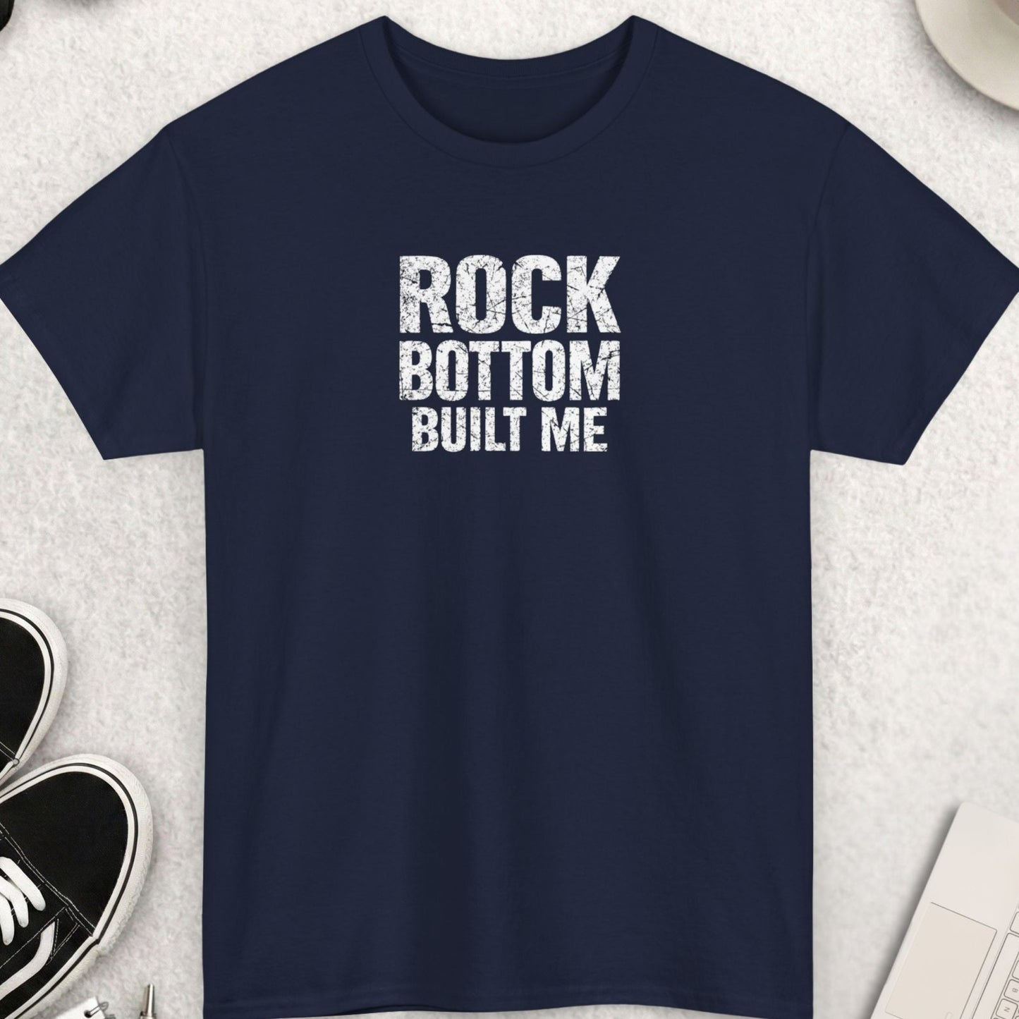 Navy blue t-shirt with “Rock Bottom Built Me” quote in cracked distressed typography