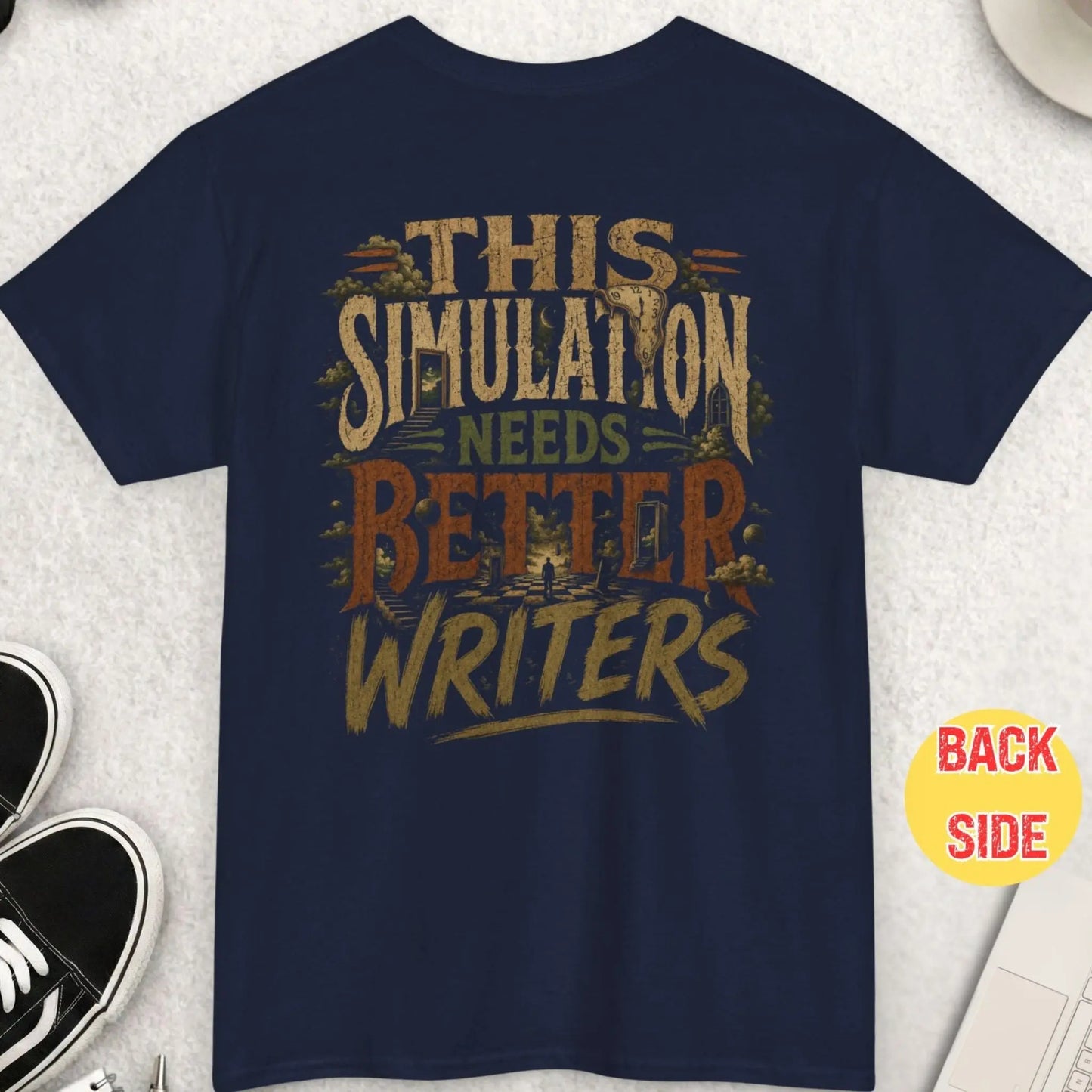 Navy blue alternative graphic tee featuring distressed typography reading “This Simulation Needs Better Writers” surrounded by surreal dark fantasy artwork with symbolic dreamscape imagery and grunge textures.