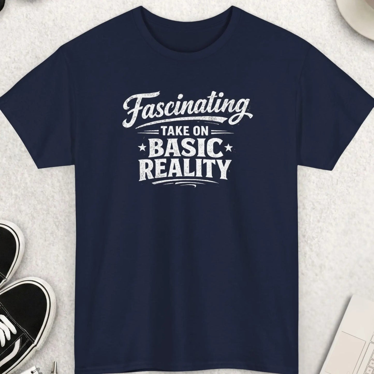 Navy blue t-shirt with white text on a light gray surface with shoes, coffee, and accessories.