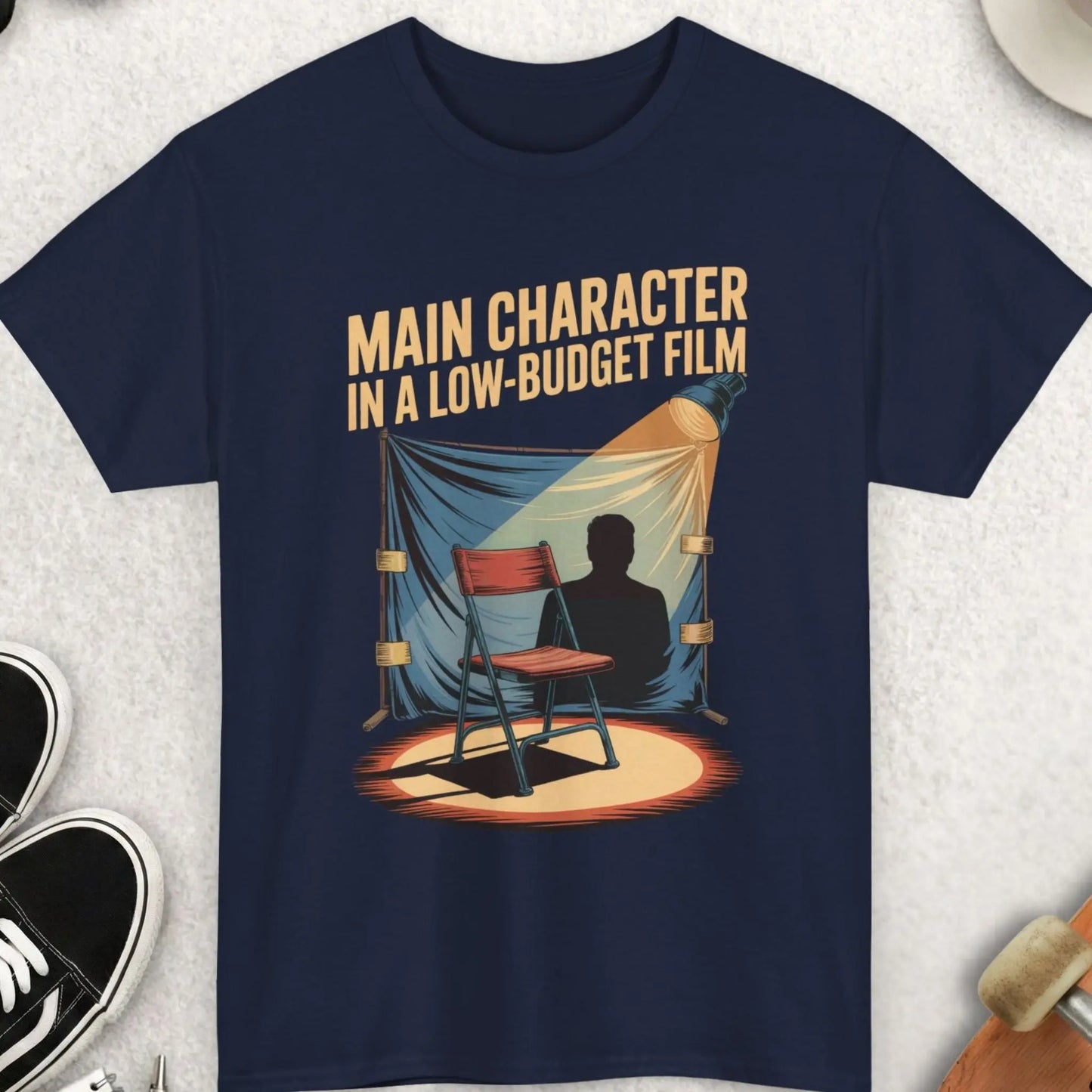 Navy blue t-shirt with graphic design and text on a light gray surface with accessories.