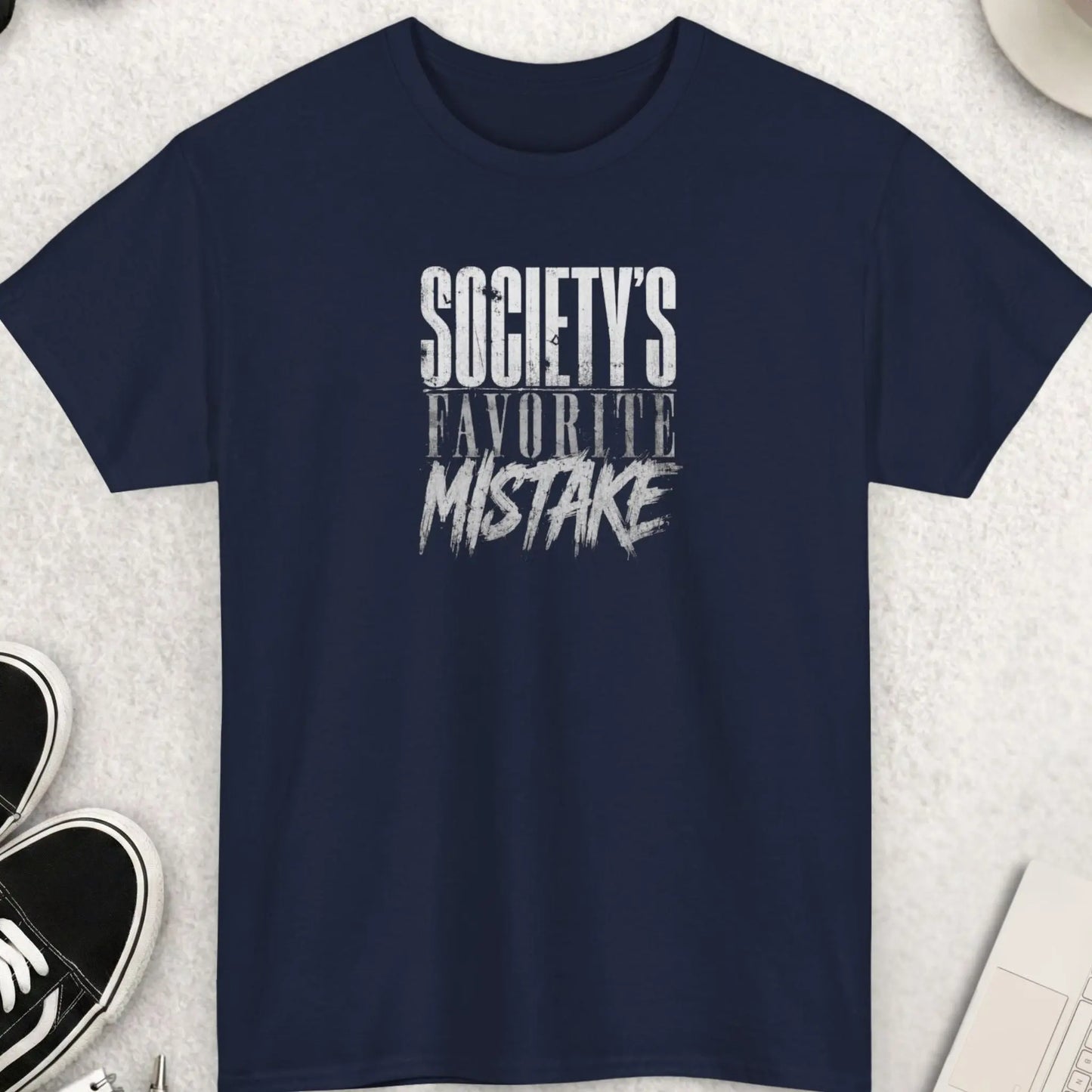 Navy blue graphic tee displaying distressed layered typography with the phrase “Society’s Favorite Mistake” in a bold alternative streetwear design.