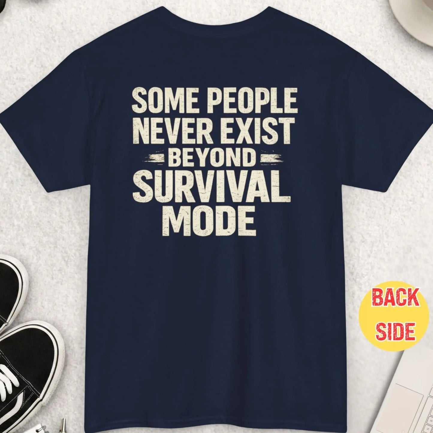 Navy blue t-shirt with distressed vintage typography displaying the phrase “Some People Never Exist Beyond Survival Mode” in a bold minimalist layout.