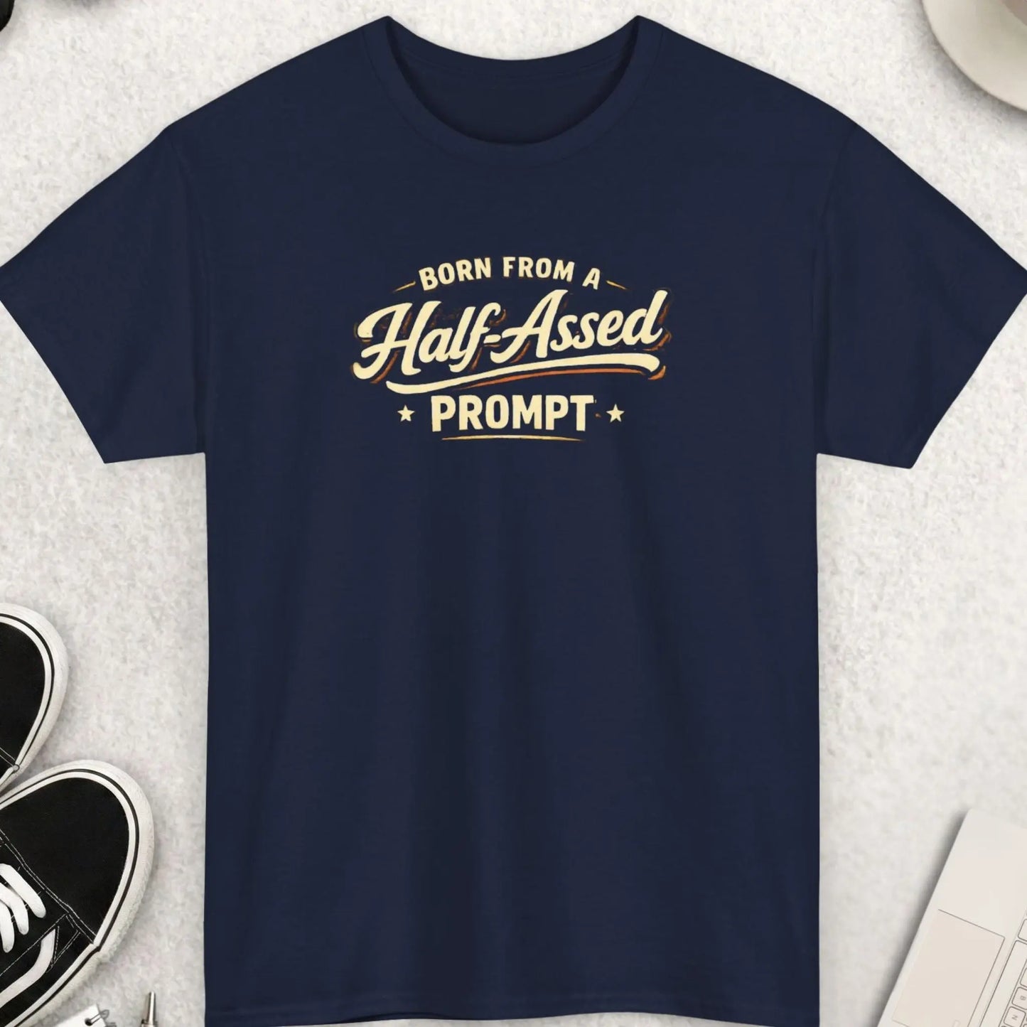 Navy blue t-shirt with humorous text design on a light gray surface with accessories.