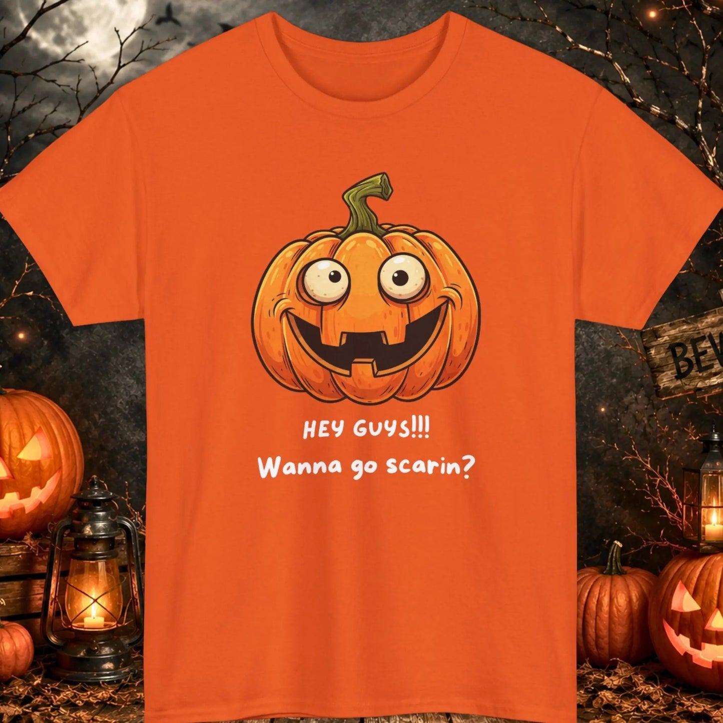 Funny Halloween pumpkin graphic t-shirt featuring a goofy smiling jack-o'-lantern with the phrase "Hey Guys!!! Wanna Go Scarin?" printed on a black shirt, spooky Halloween apparel for men and women, perfect for fall and October celebrations.