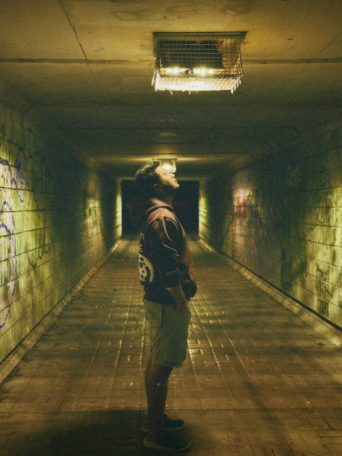 a man standing in a dark tunnel with graffiti on the walls