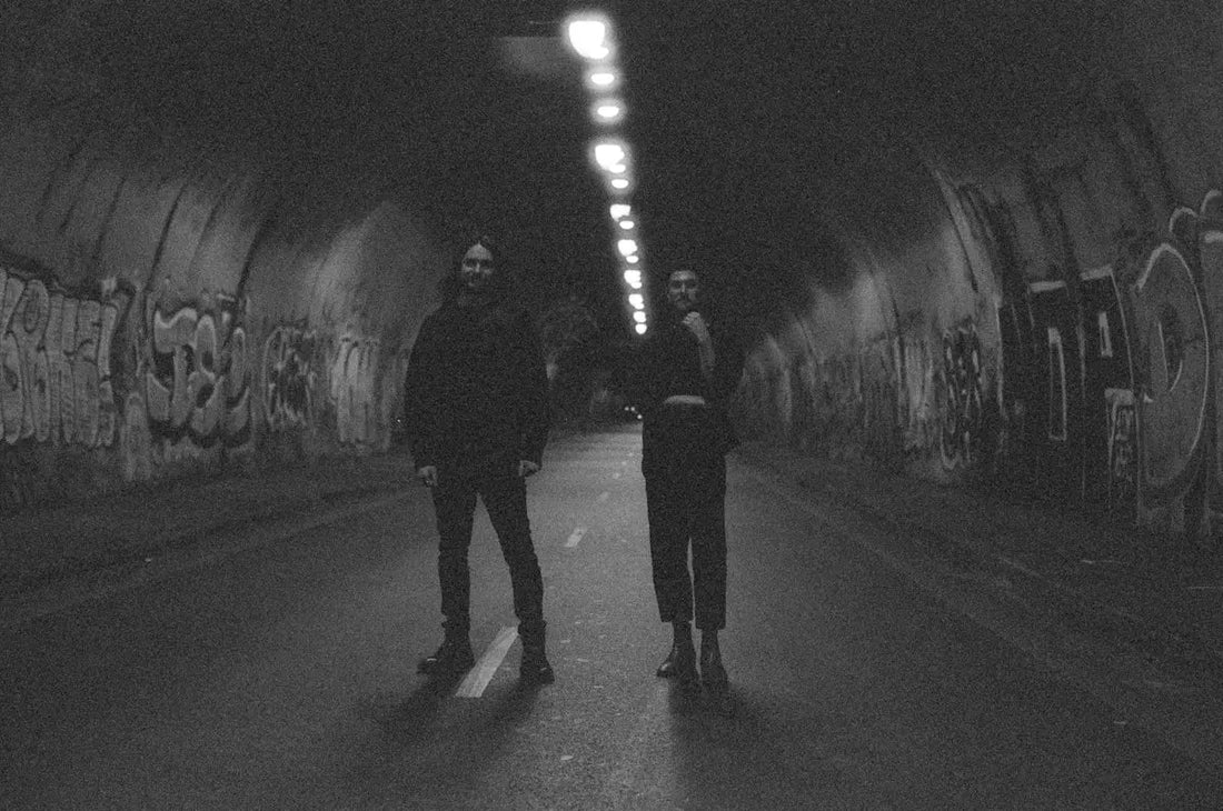 Two people stand in a dimly lit tunnel.