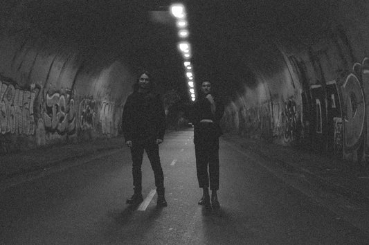 Two people stand in a dimly lit tunnel.