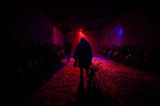 A person walks down a dark, red-lit hallway.