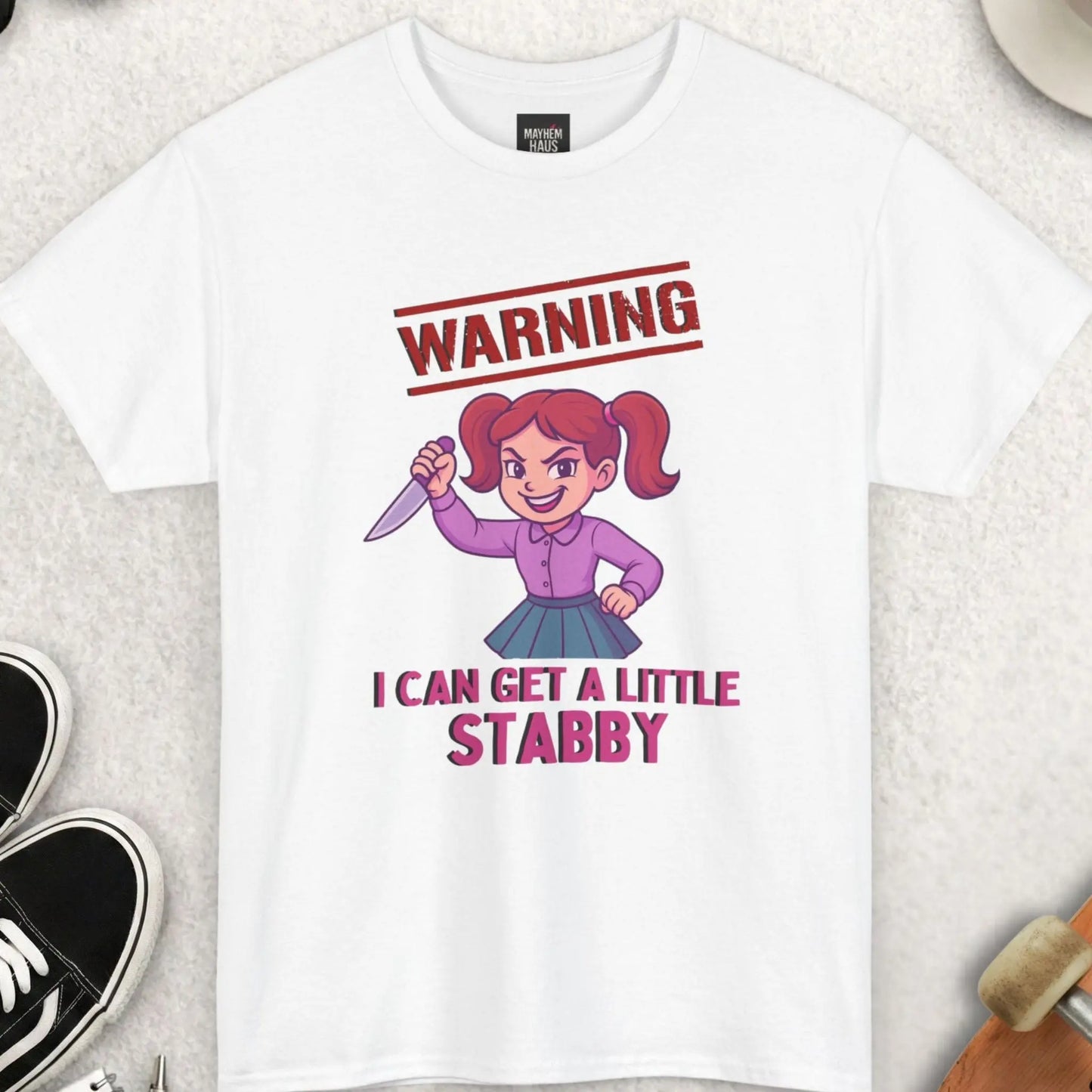 White t-shirt with cartoon character and text on a light surface with accessories around