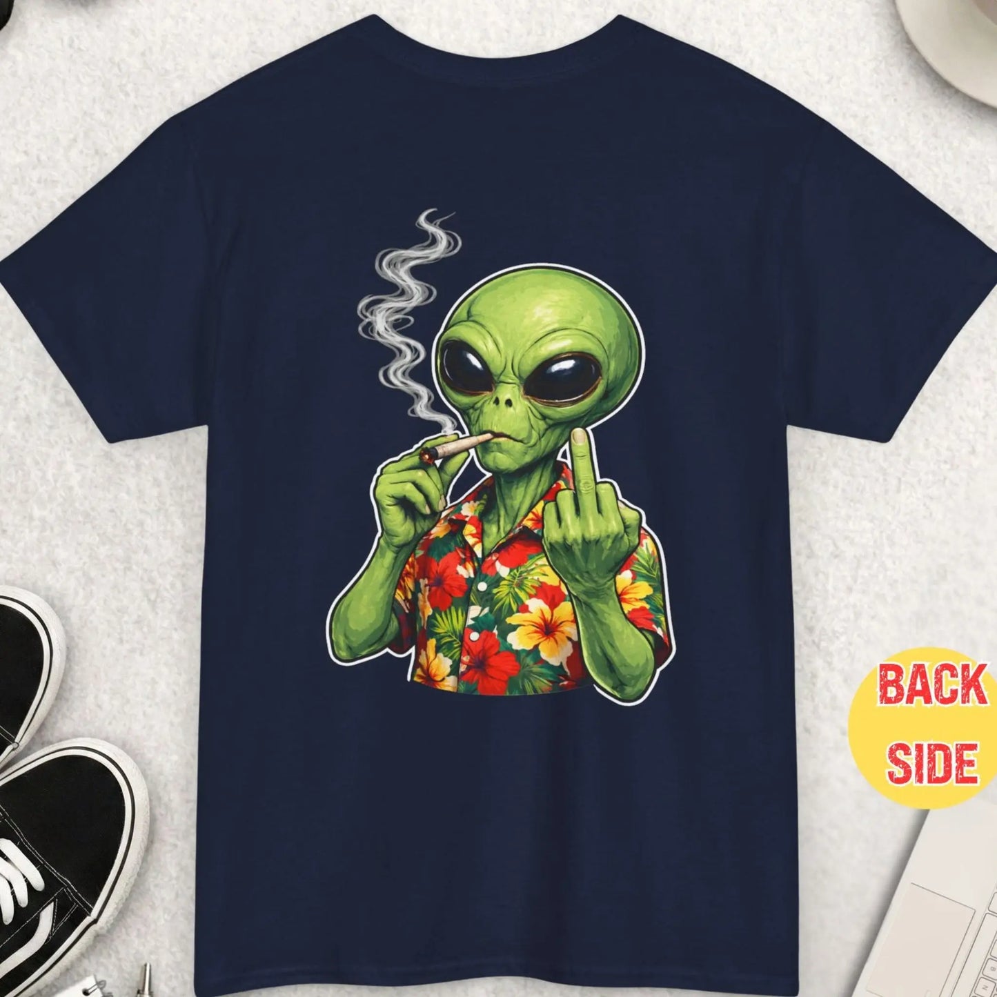 Navy blue t-shirt with an alien smoking a cigarette on a light gray surface with accessories.
