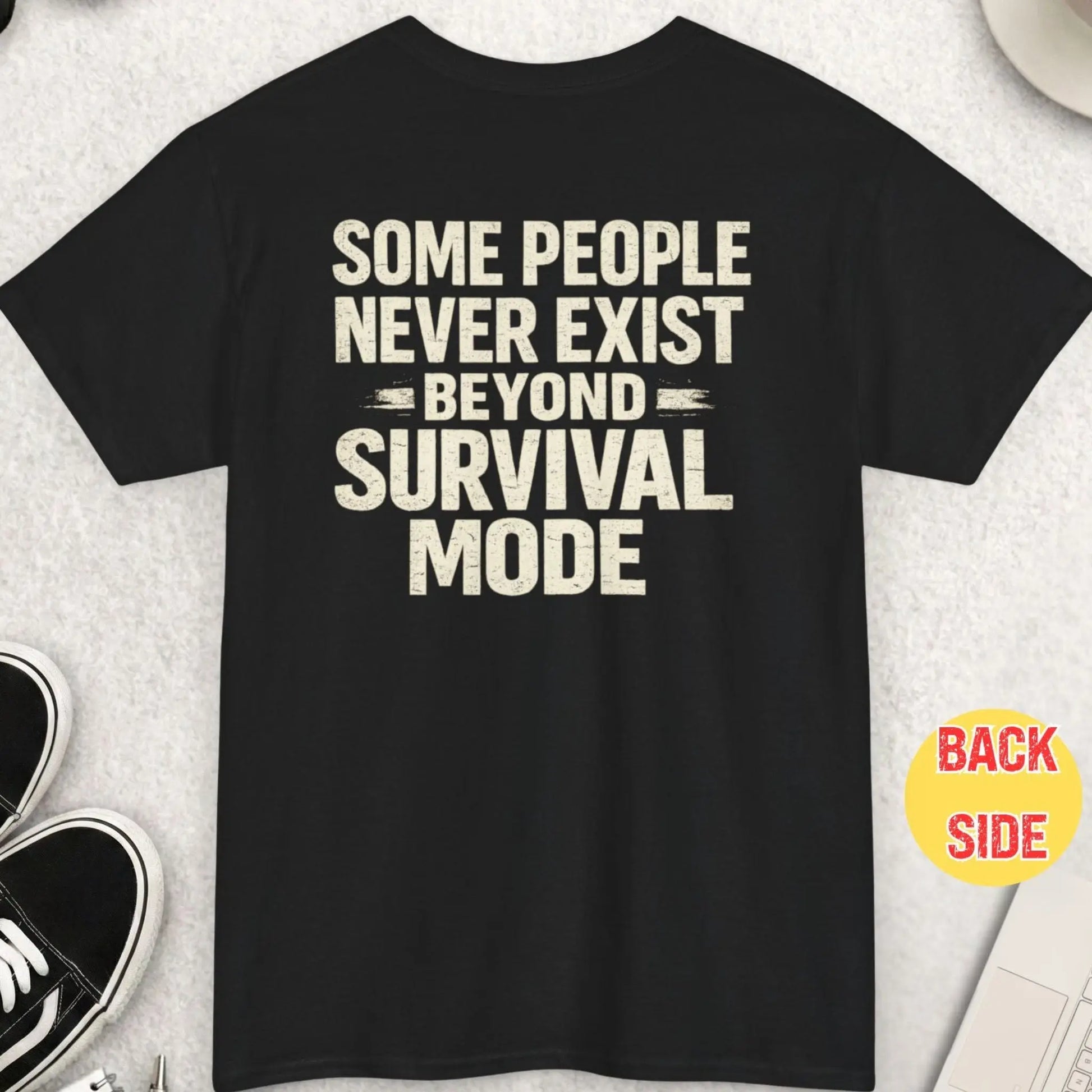 Black t-shirt featuring distressed bold typography reading “Some People Never Exist Beyond Survival Mode” in a minimalist high-contrast design.