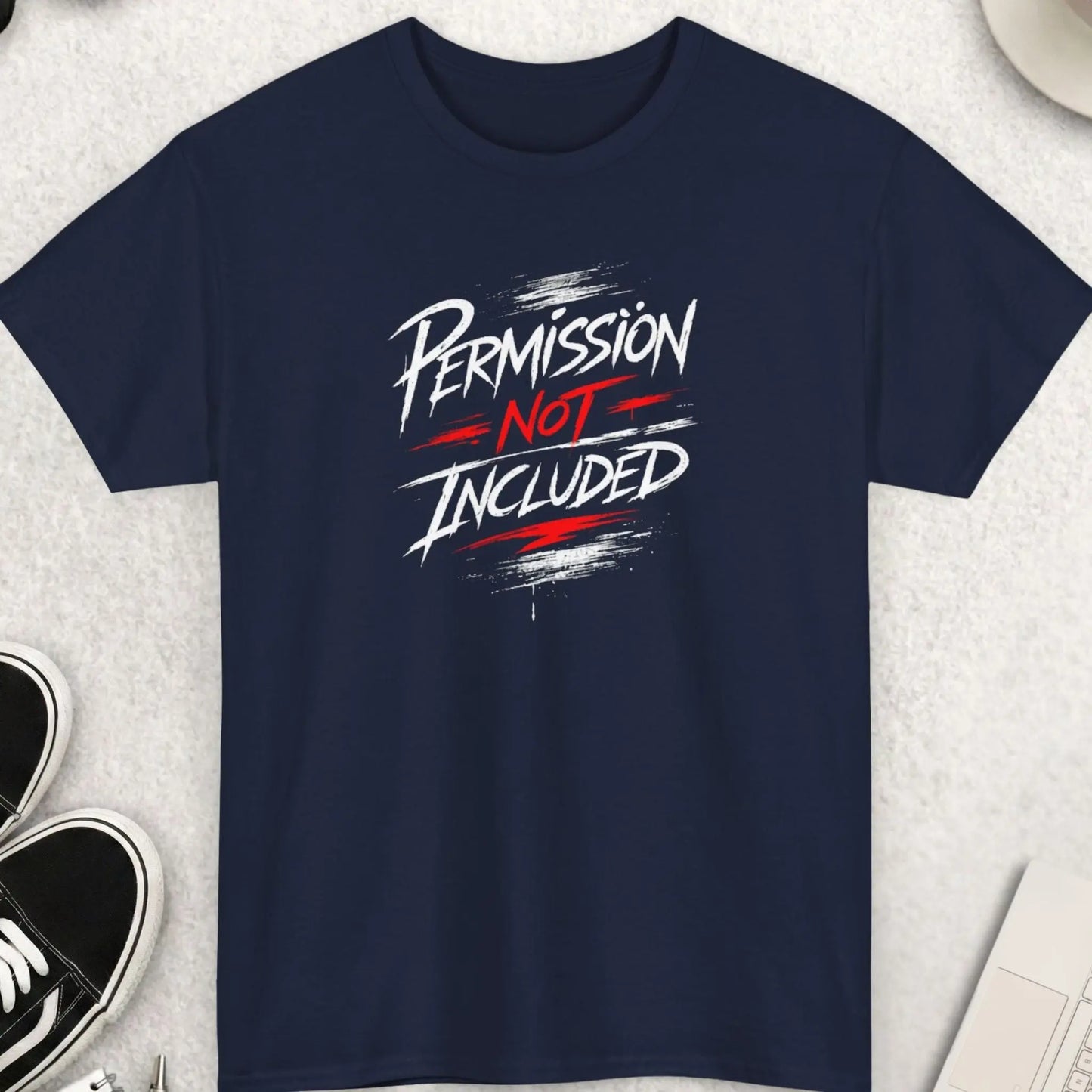 Navy Blue t-shirt with 'PERMISSION NOT INCLUDED' text on a light gray surface with shoes, sunglasses, and a cup.