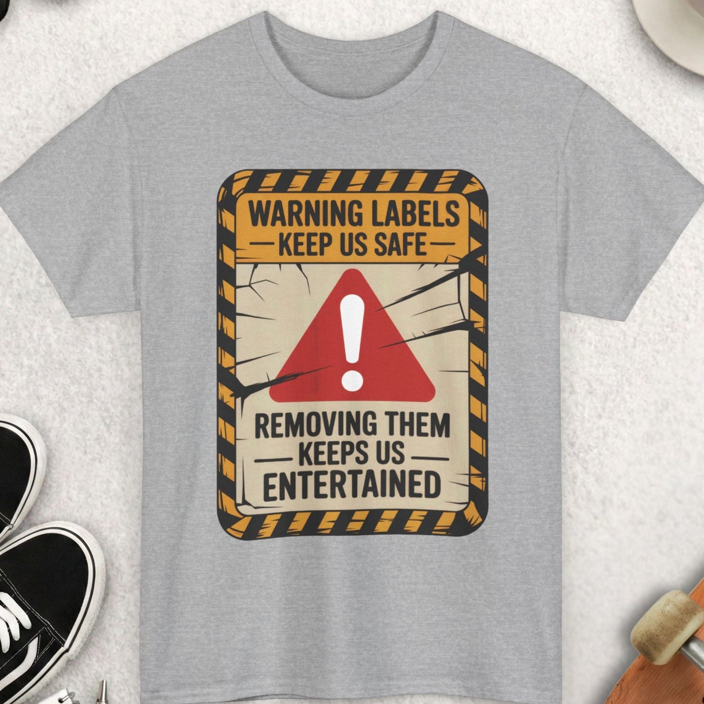 Gray t-shirt with a warning label design on a textured surface with accessories.