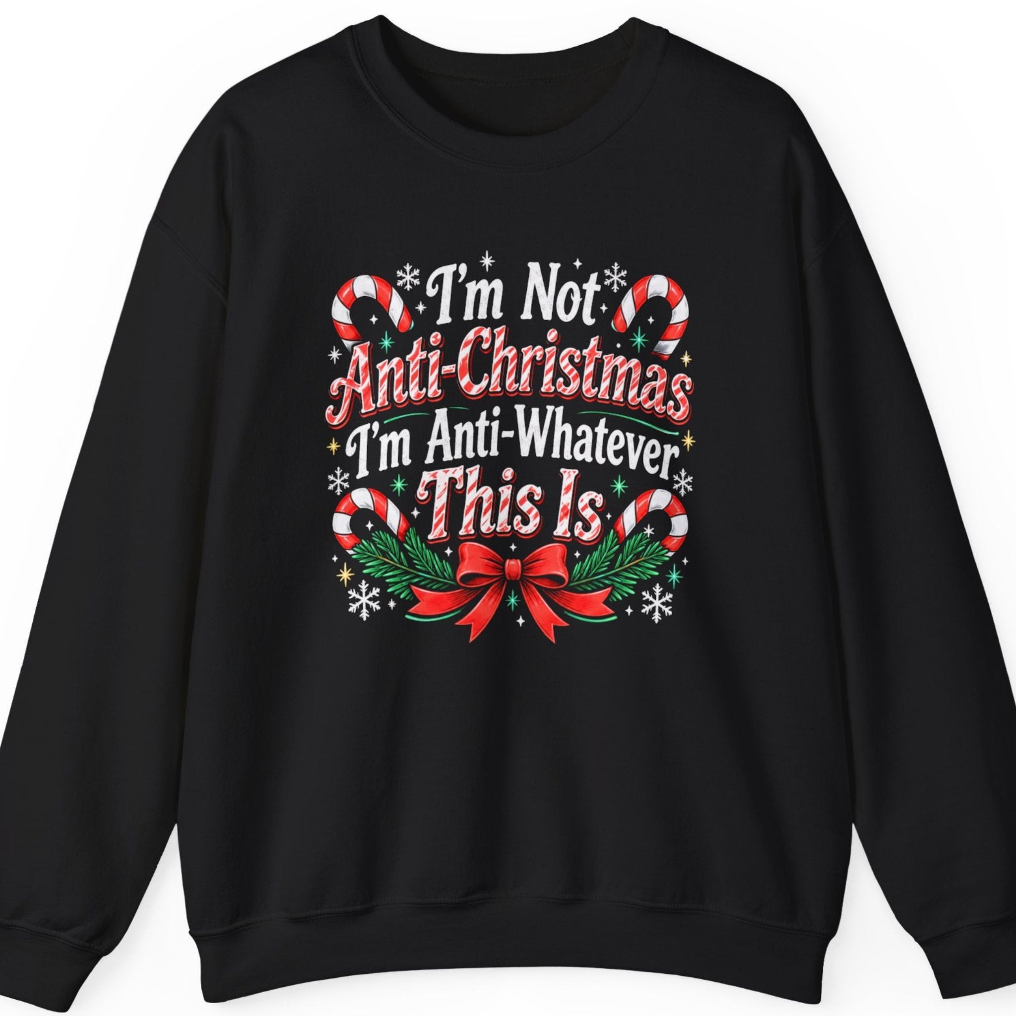 Mayhem Haus “I'm Not Anti-Christmas I'm Anti-Whatever This Is” black crewneck sweatshirt featuring bold red and white sarcastic Christmas lettering with a vintage distressed finish, accented by striped candy canes, festive holly, evergreen foliage, white snowflakes, golden stars, and a large red Christmas bow.