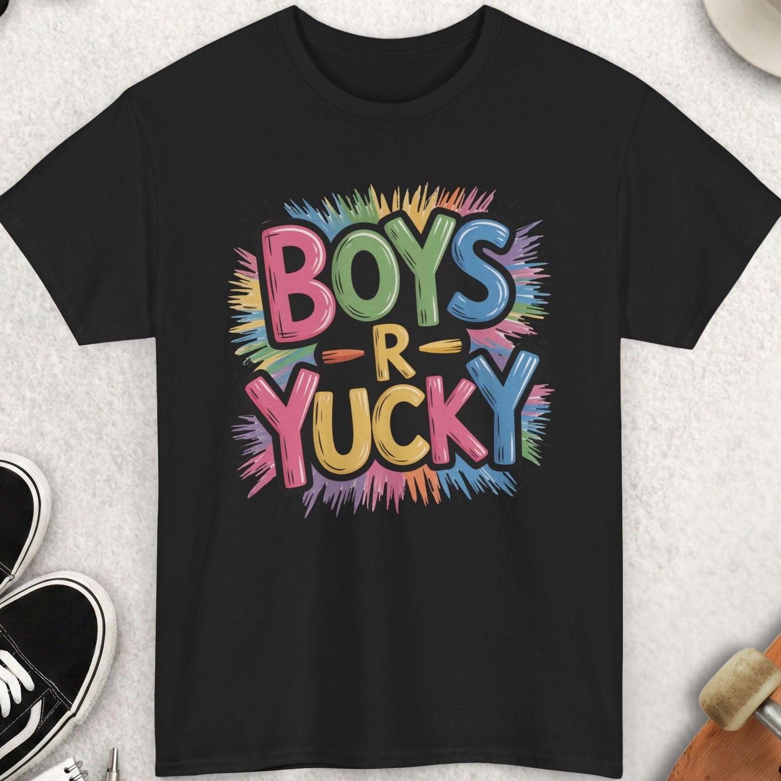 Black t-shirt with colorful 'Boys R Yucky' text on a light gray surface with accessories.