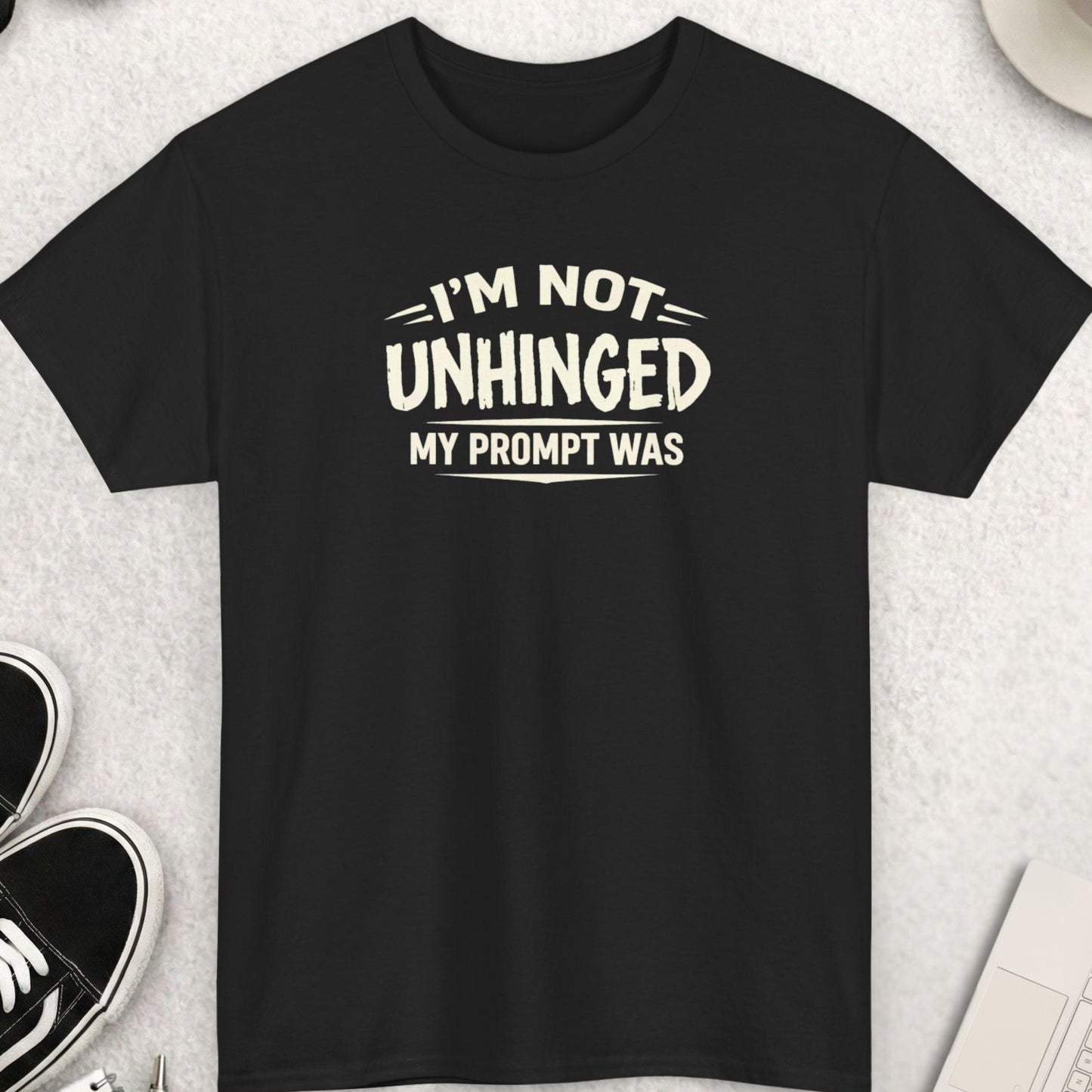 Black t-shirt with humorous text on a light gray surface with accessories.