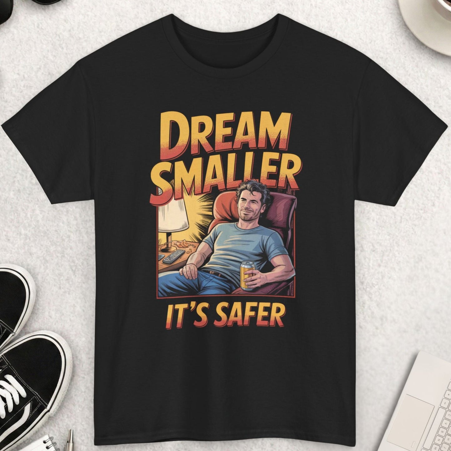 Black t-shirt with graphic design and text on a light gray surface with accessories.