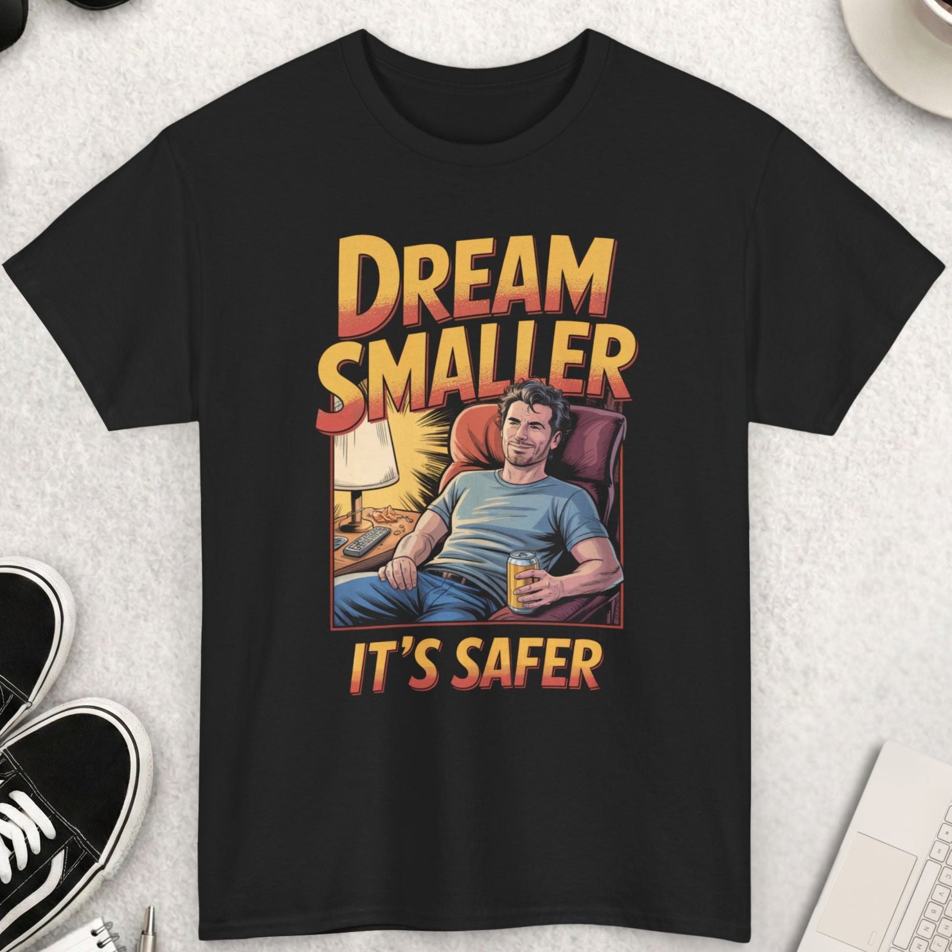 Black t-shirt with graphic design and text on a light gray surface with accessories.