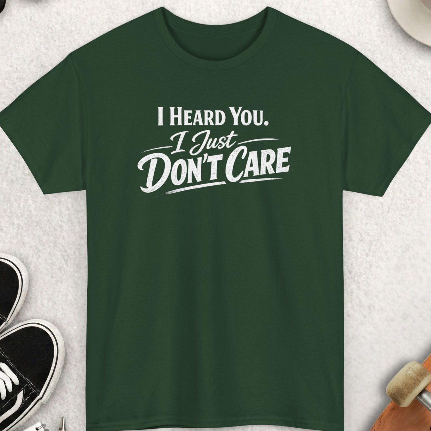 Green t-shirt with 'I Heard You, I Just Don't Care' text on a light gray surface with accessories.