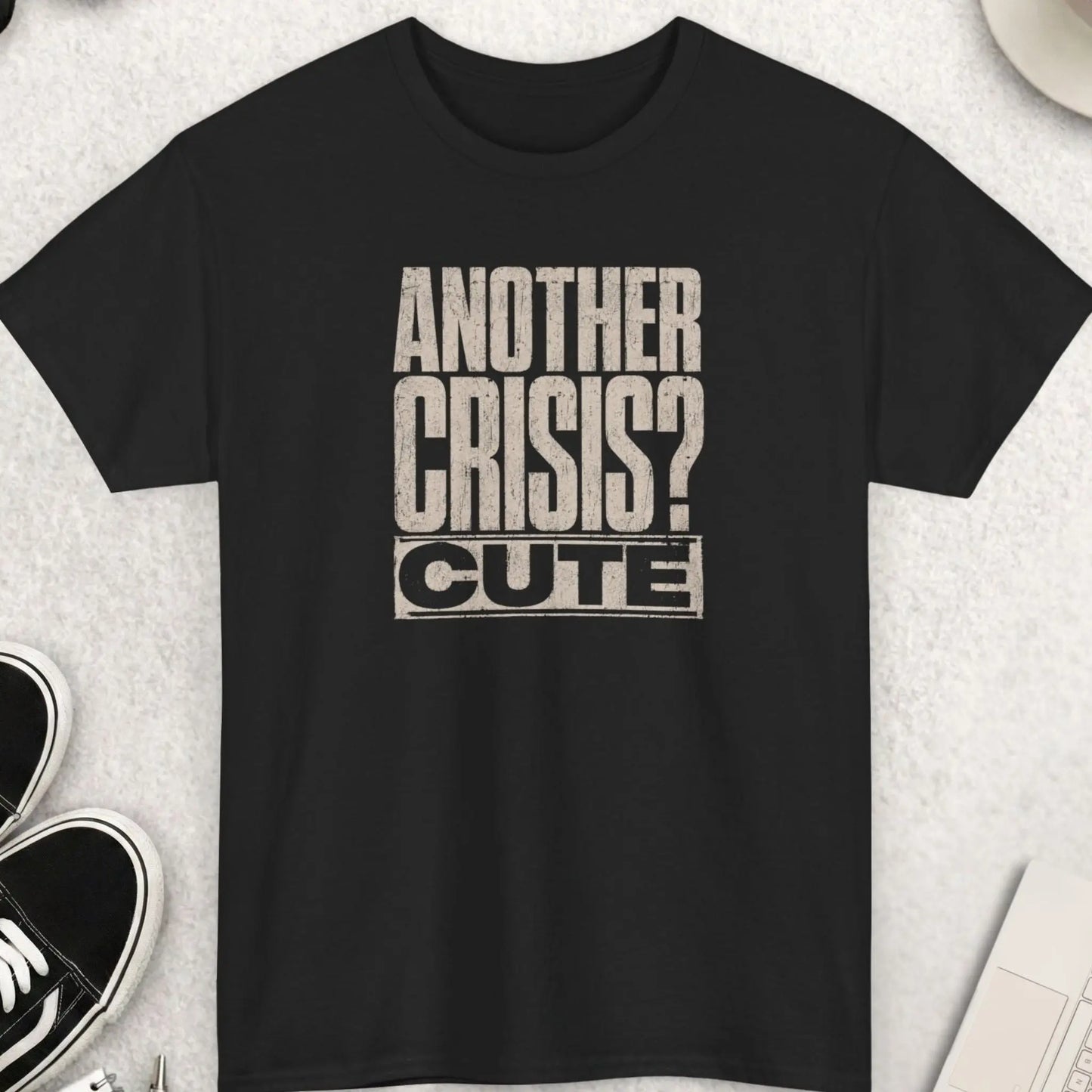 Distressed typography t-shirt design reading “Another Crisis? Cute.” in oversized vintage cream lettering on a black shirt with bold sarcastic dark humor aesthetic.