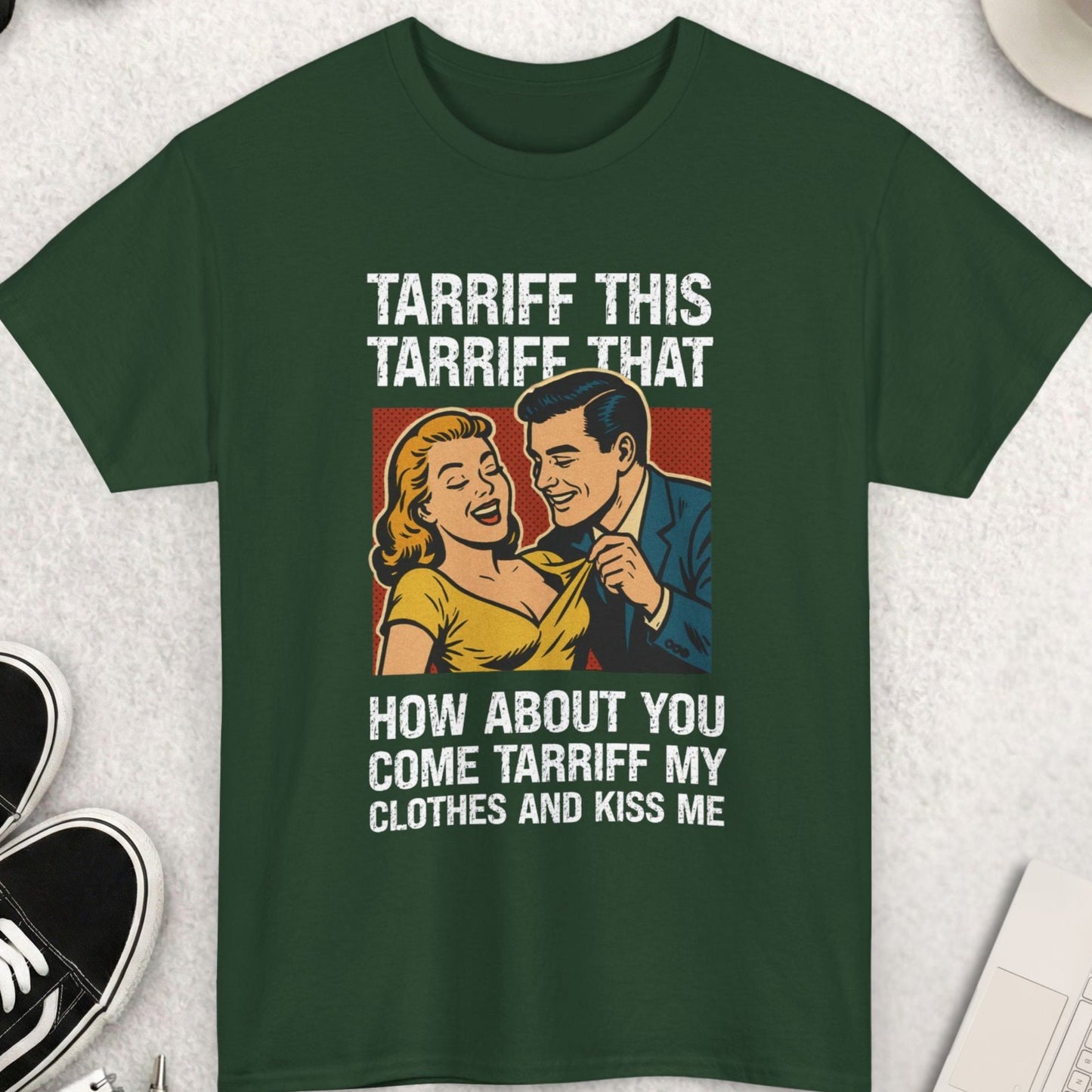 Green t-shirt with graphic and text on a light gray surface with accessories.