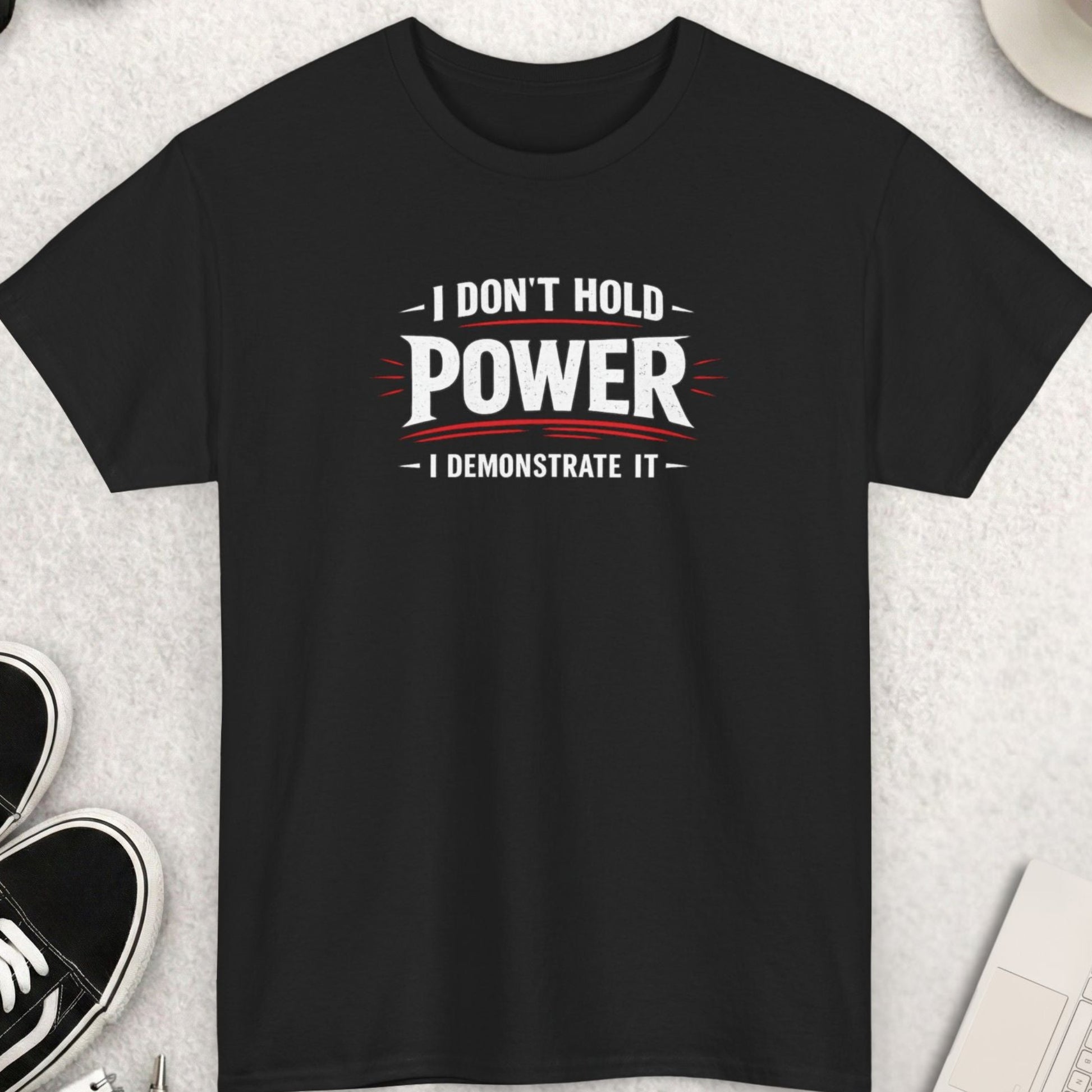 Black t-shirt with motivational quote on a light gray surface with accessories.