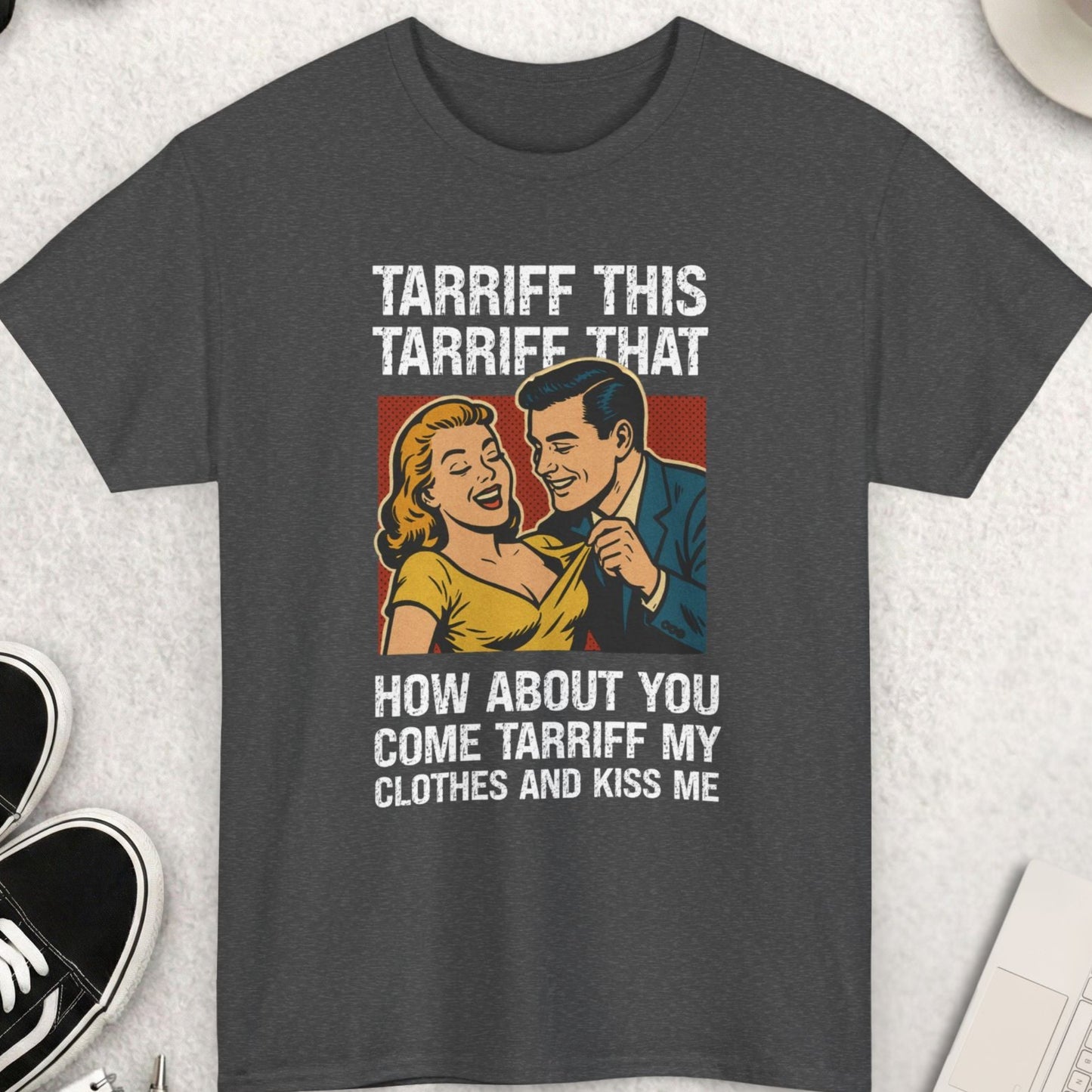 Gray t-shirt with graphic design and text on a light gray surface with accessories.