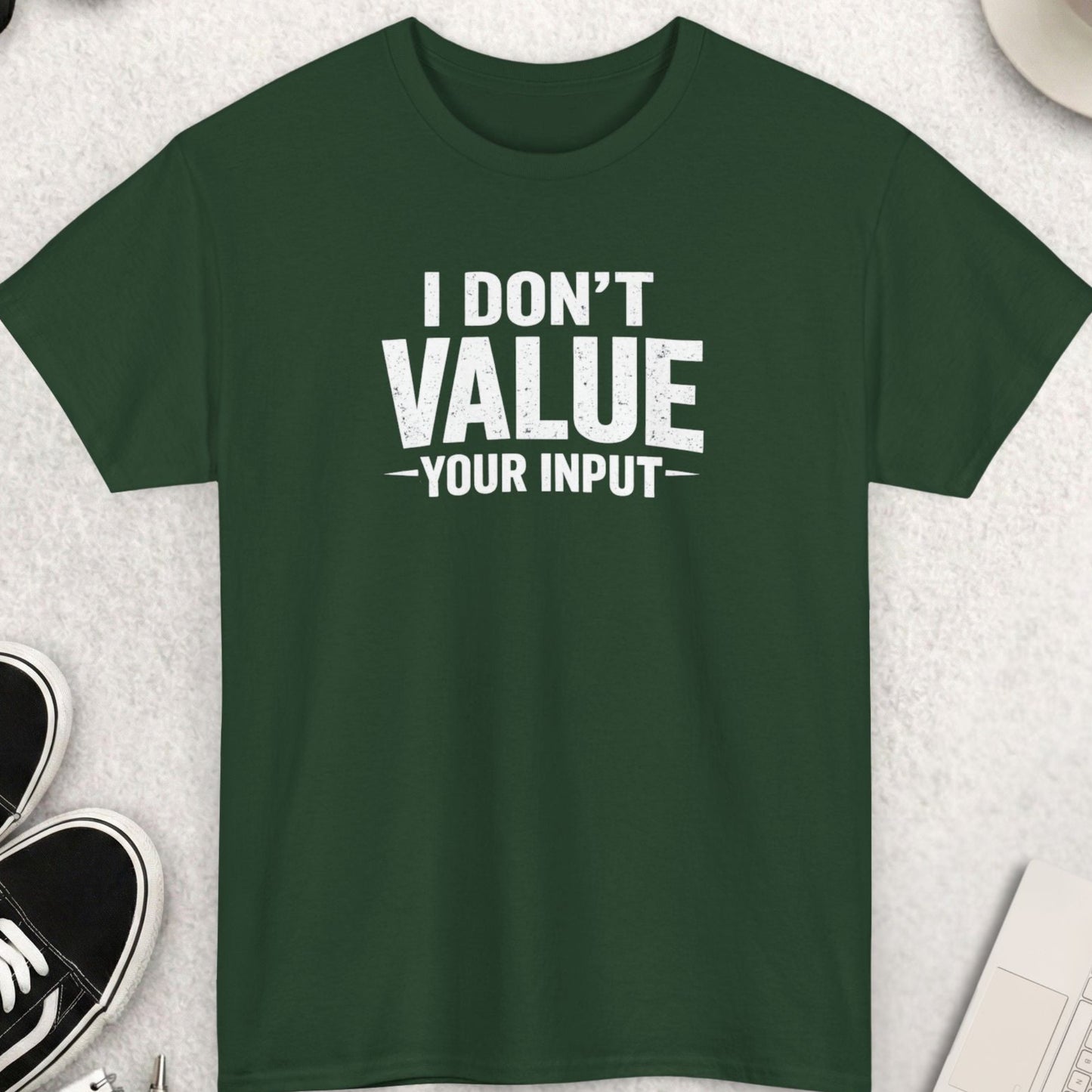 Green t-shirt with 'I Don't Value Your Input' text on a light gray surface with accessories.
