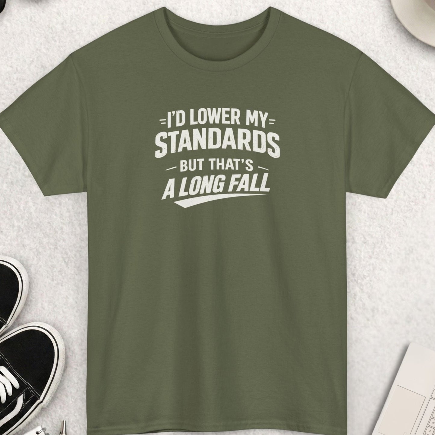 Green t-shirt with humorous text on a light gray surface with accessories.