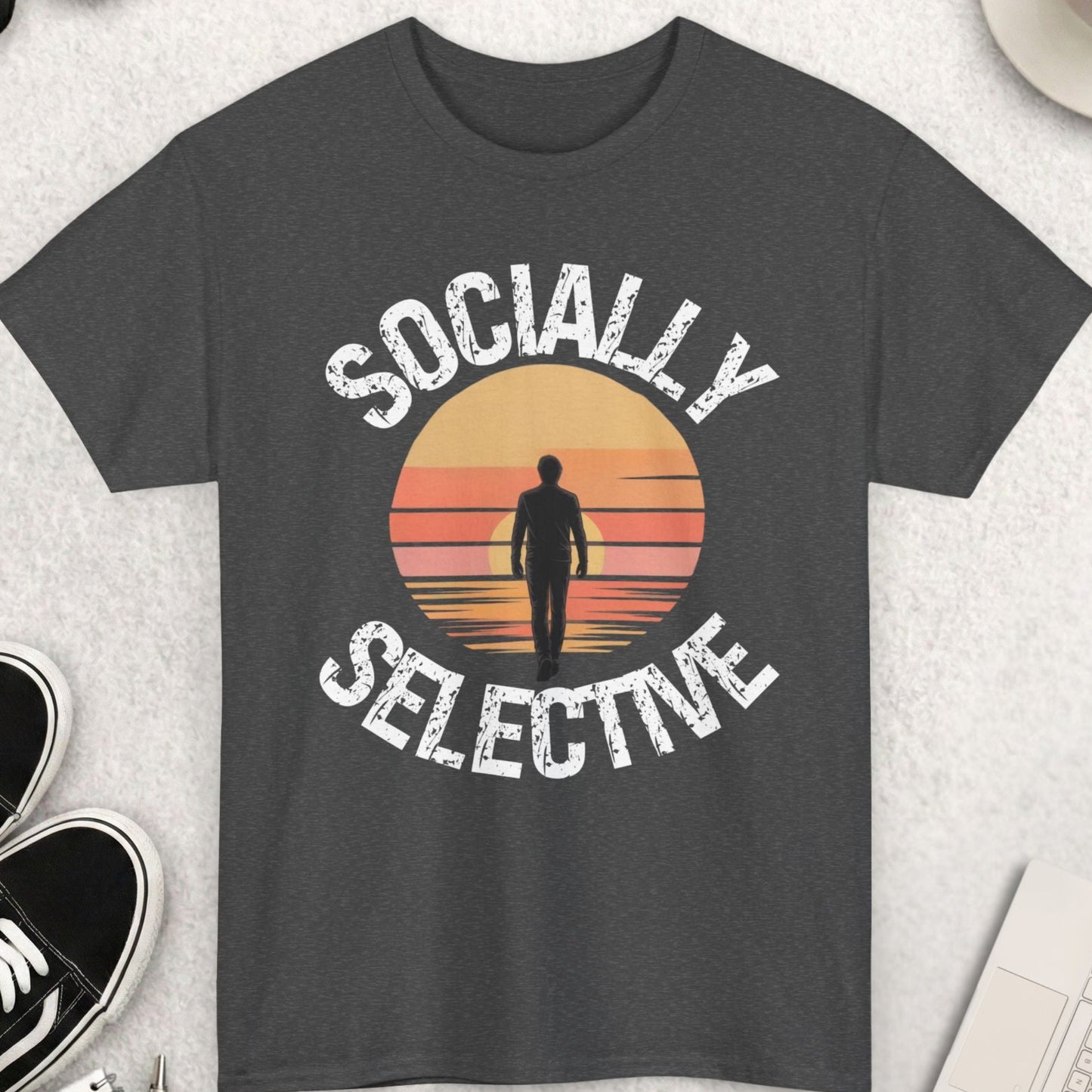 Dark gray t-shirt with 'Socially Selective' design on a light gray surface with accessories.