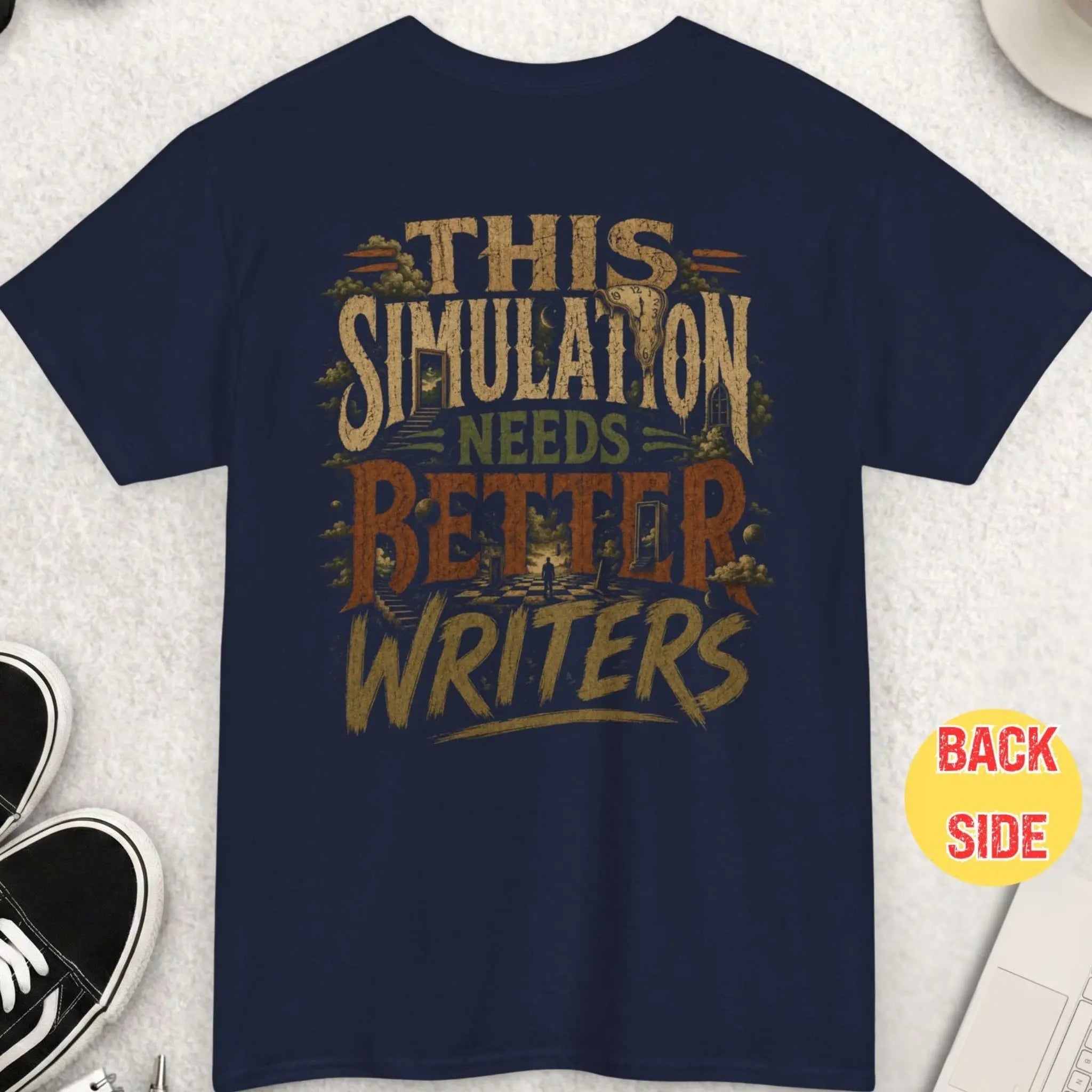 Navy blue alternative graphic tee featuring distressed typography reading “This Simulation Needs Better Writers” surrounded by surreal dark fantasy artwork with symbolic dreamscape imagery and grunge textures.