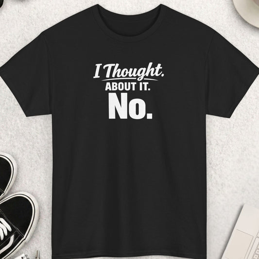 Black t-shirt with 'I Thought About It. No.' text on a light gray surface with shoes, coffee, and accessories.