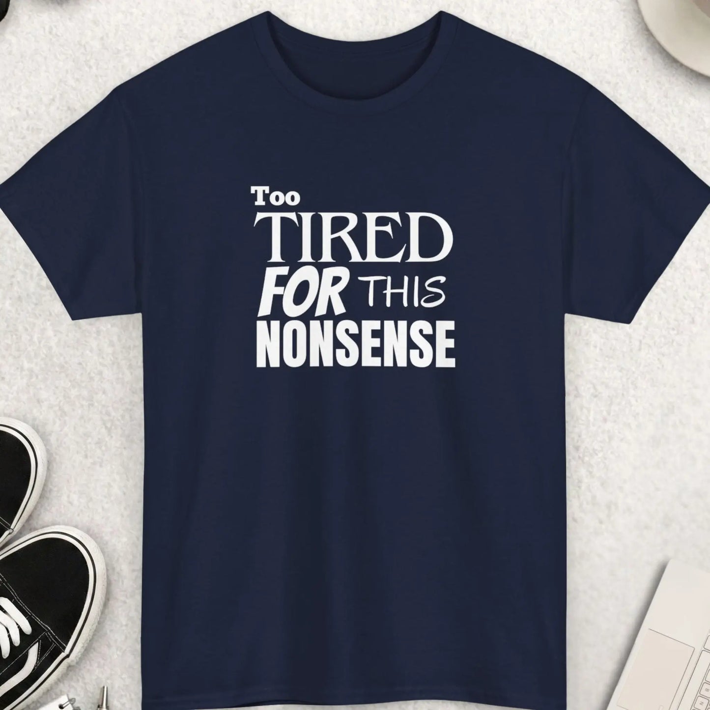 Navy blue t-shirt with 'Too Tired For This Nonsense' text on a light gray surface with accessories.