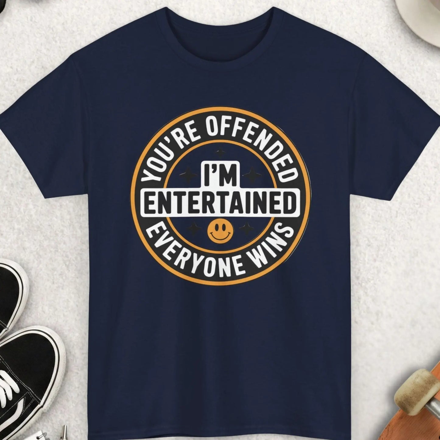 Navy blue t-shirt with humorous graphic design on a light gray surface with accessories.