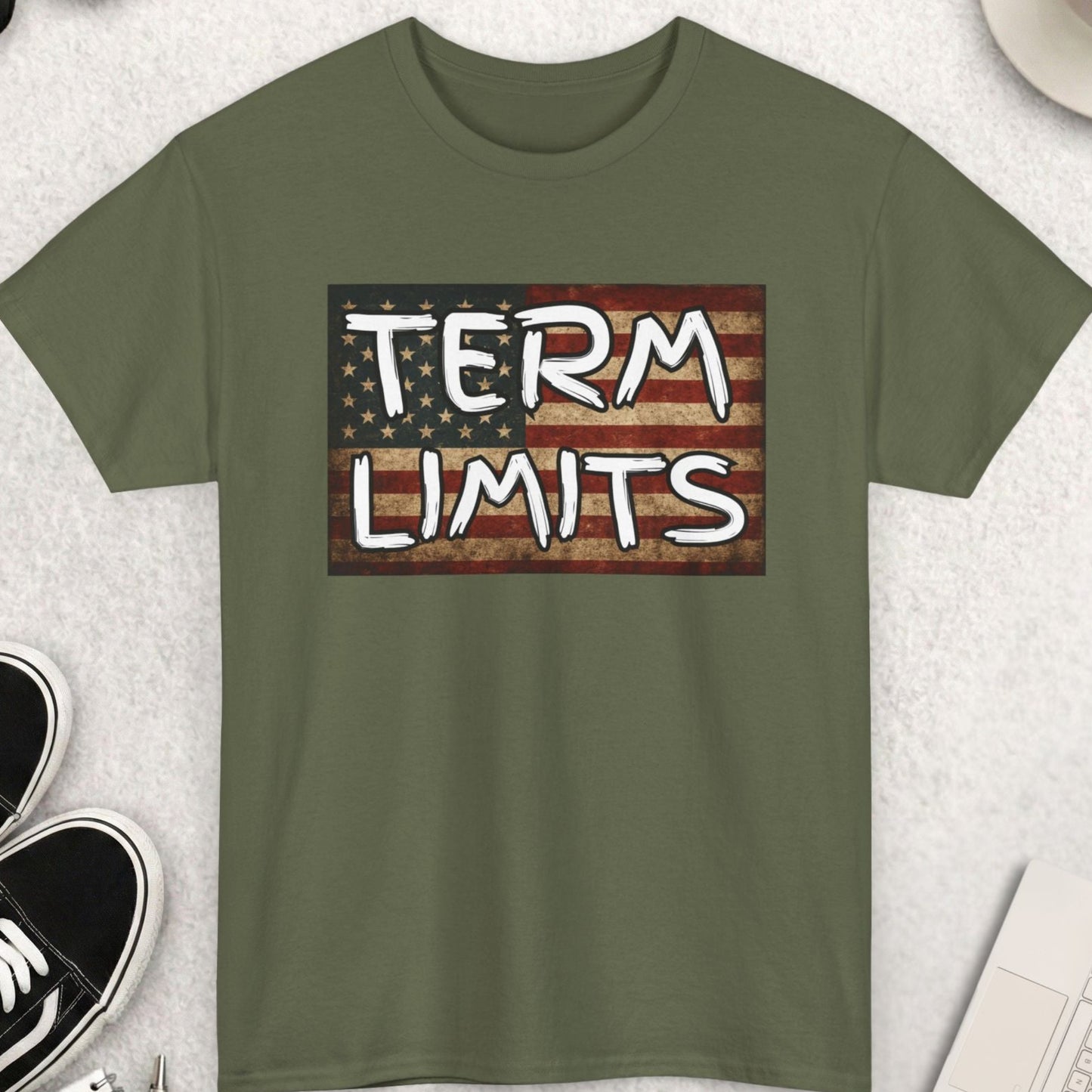 Green t-shirt with 'TERM LIMITS' graphic on a light gray surface with accessories.