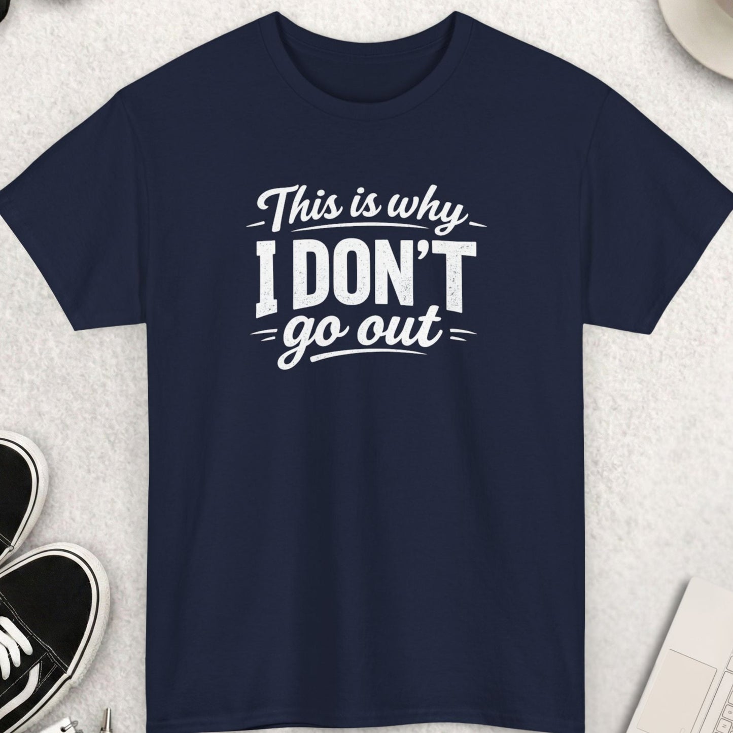 Navy blue t-shirt with white text on a light gray surface with accessories.