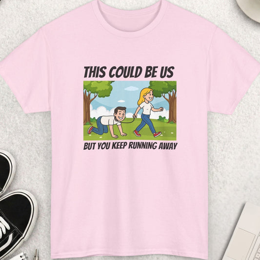 Pink t-shirt with a graphic and text on a light gray surface with accessories around.