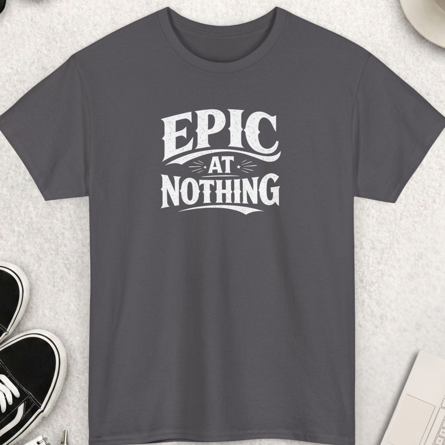 Gray t-shirt with 'Epic at Nothing' text on a light gray surface with accessories.
