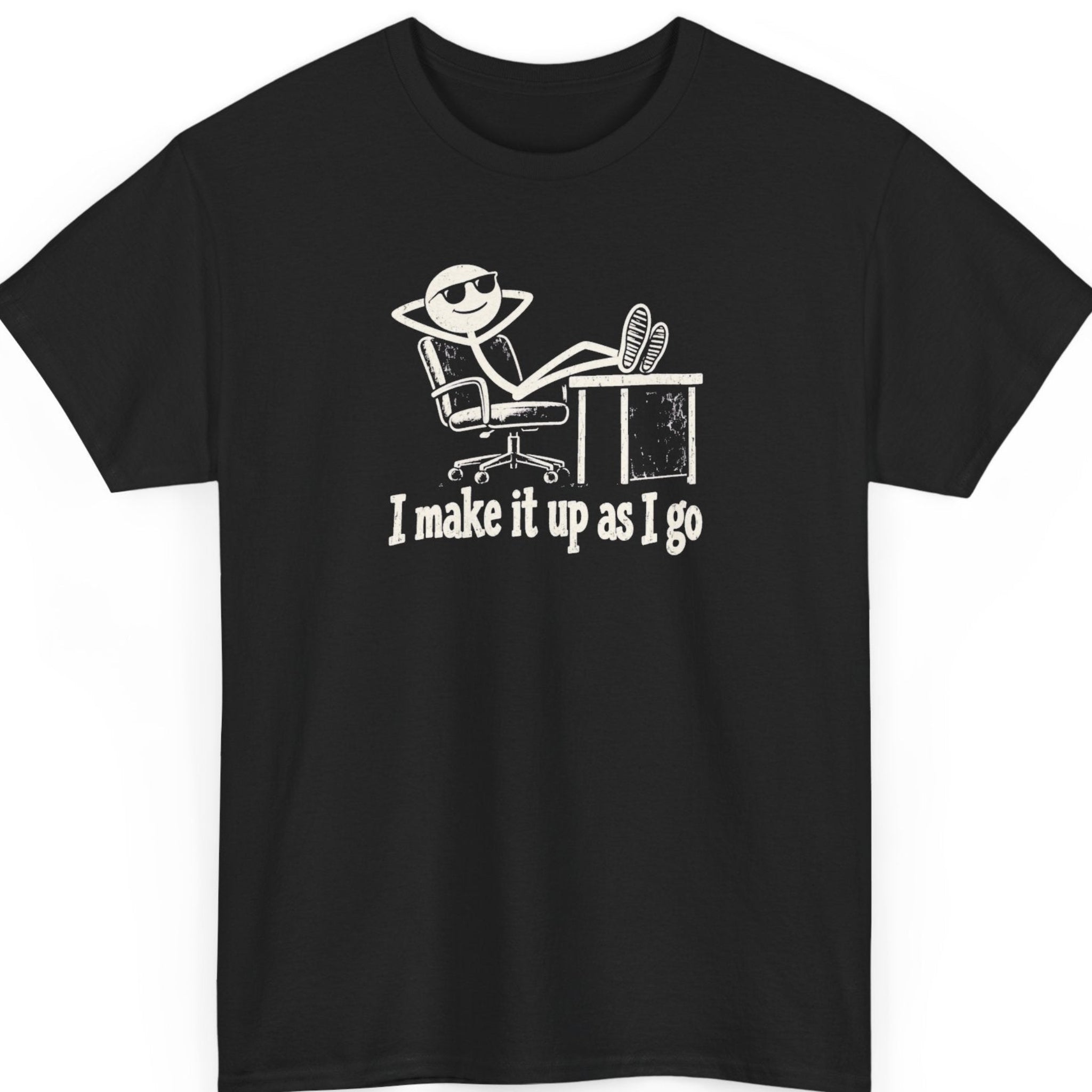 Mayhem Haus “I Make It Up As I Go” black t-shirt featuring a distressed white stick figure wearing sunglasses, reclining in an office chair with feet on a desk, above the humorous statement in vintage-style lettering.