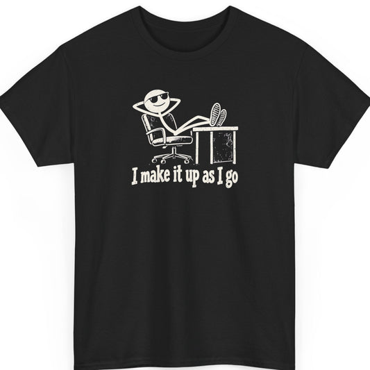 Mayhem Haus “I Make It Up As I Go” black t-shirt featuring a distressed white stick figure wearing sunglasses, reclining in an office chair with feet on a desk, above the humorous statement in vintage-style lettering.