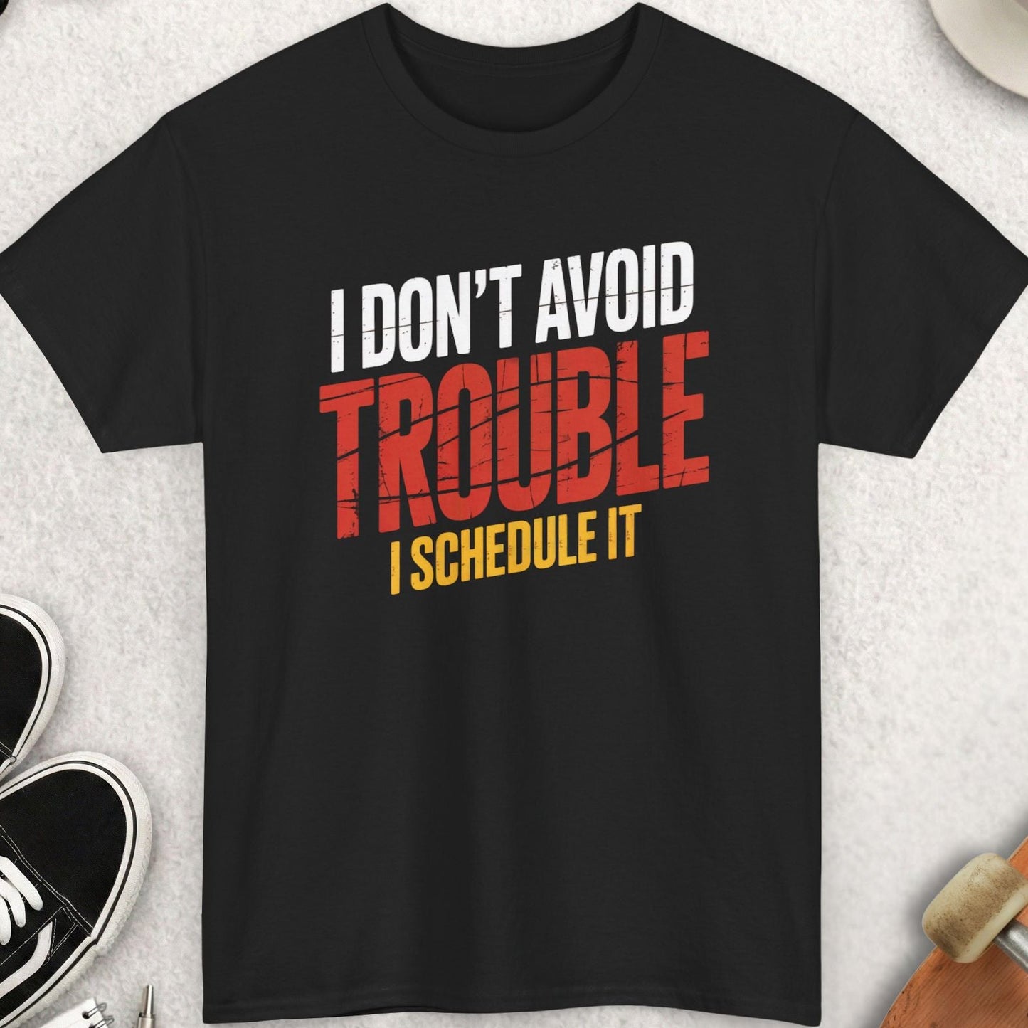 Black t-shirt with humorous text design on a light gray surface with accessories.
