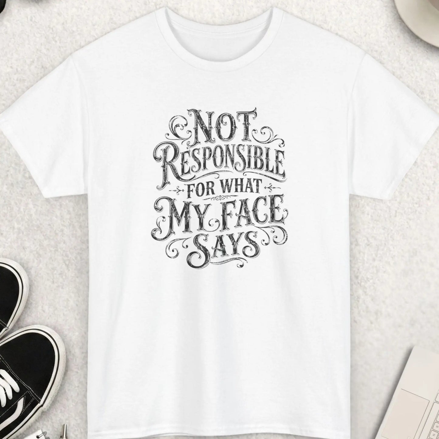 White sarcastic typography t-shirt featuring distressed black vintage-style lettering reading “Not Responsible For What My Face Says” with ornate decorative flourishes and a classic retro aesthetic.