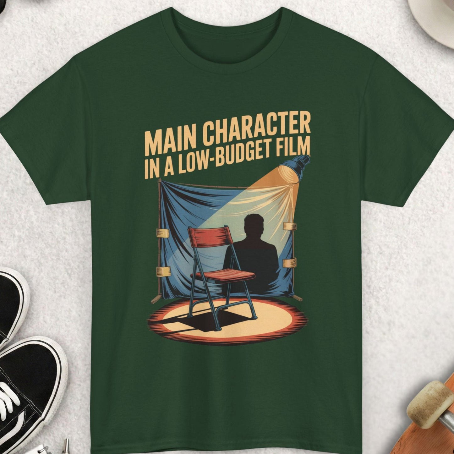 Green t-shirt with a graphic design and text on a light gray surface with accessories.