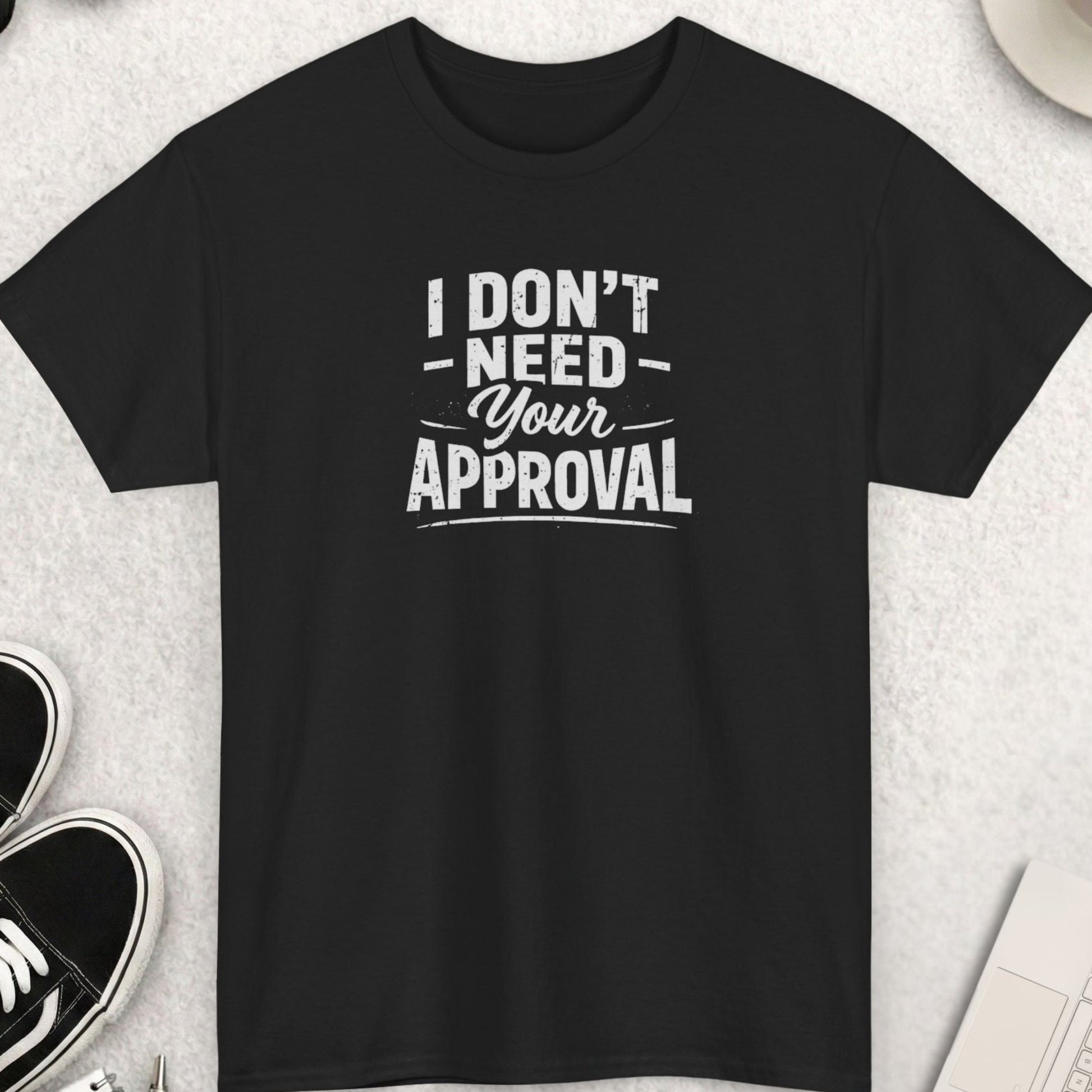 Black t-shirt with 'I don't need your approval' text on a light gray surface with shoes, coffee, and accessories.