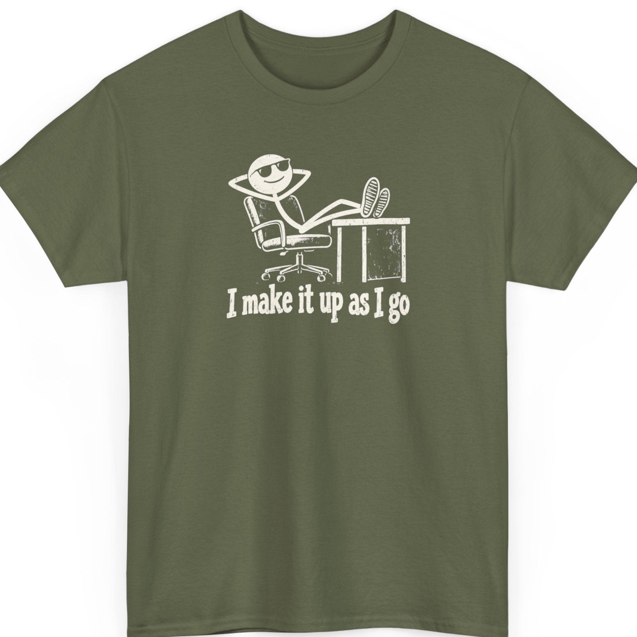 Mayhem Haus “I Make It Up As I Go” military green t-shirt featuring a humorous white stick figure reclining in a rolling office chair with feet on a desk, accompanied by bold vintage-inspired lettering.
