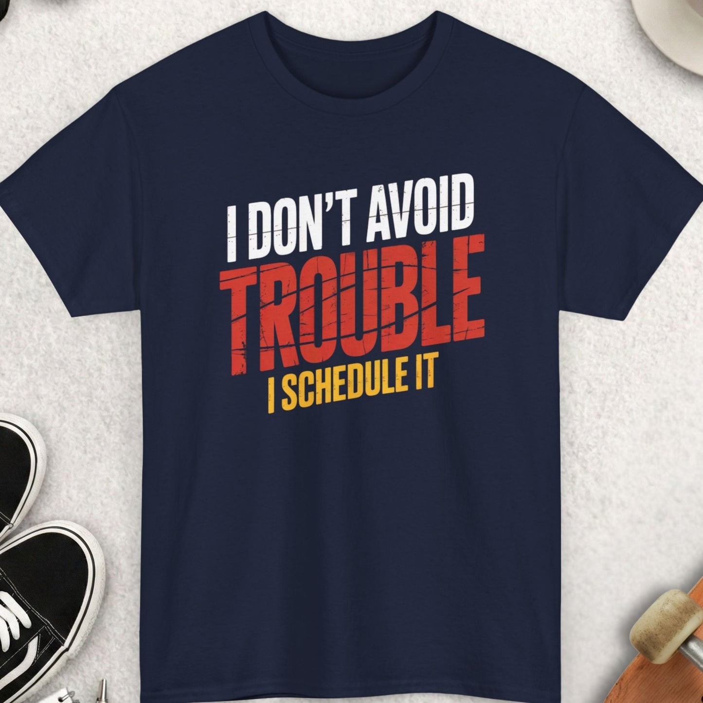 Navy blue t-shirt with humorous text design on a light gray surface with accessories.