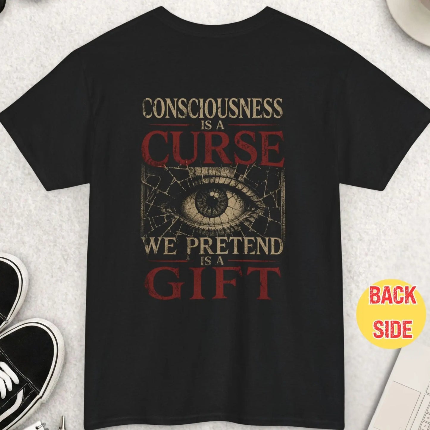 Black t-shirt featuring distressed typography reading “Consciousness is a curse we pretend it’s a gift” with cracked all-seeing eye graphic