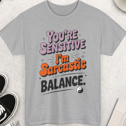 Gray t-shirt with humorous text design on a light surface with accessories.