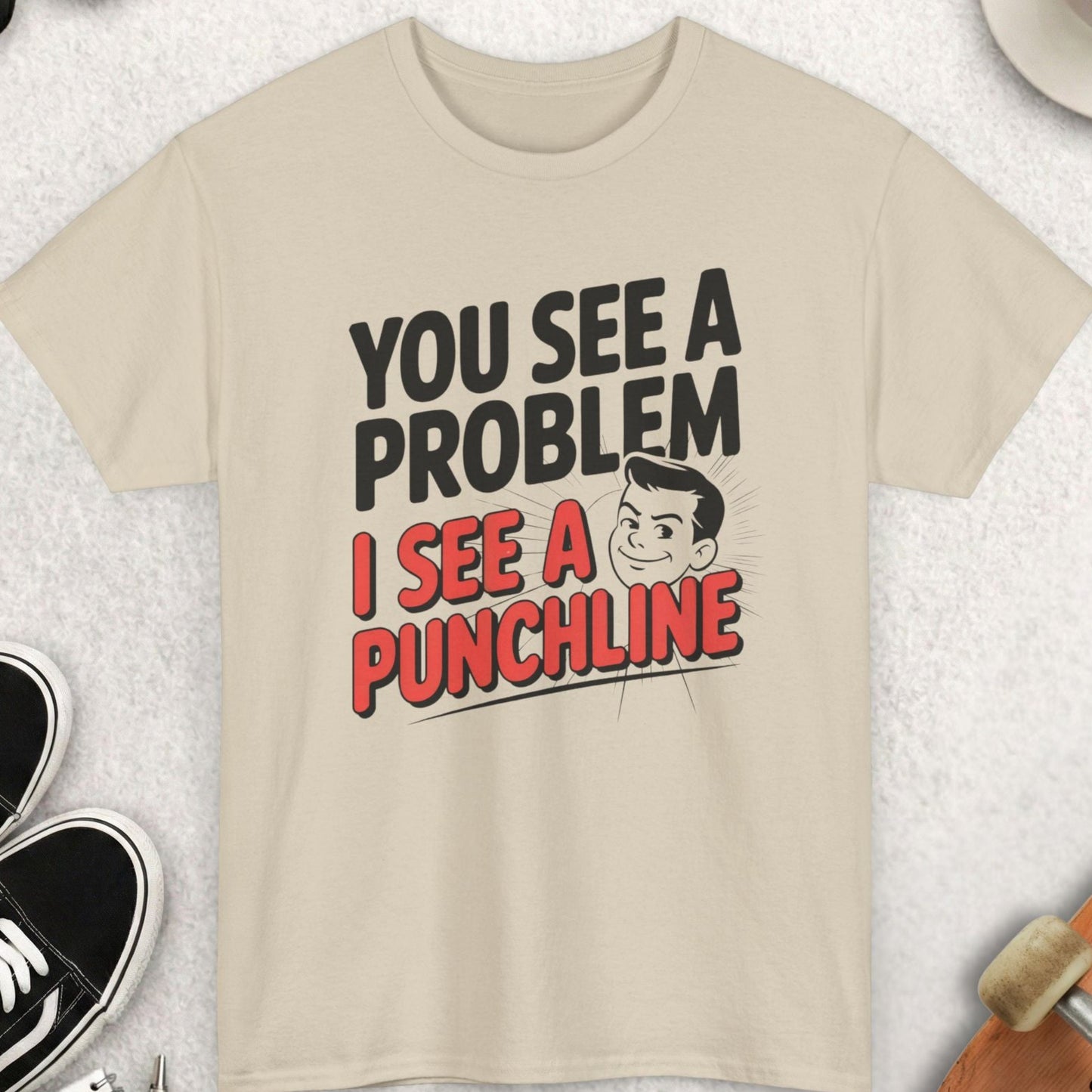 Beige t-shirt with humorous text design on a light gray surface with accessories around.